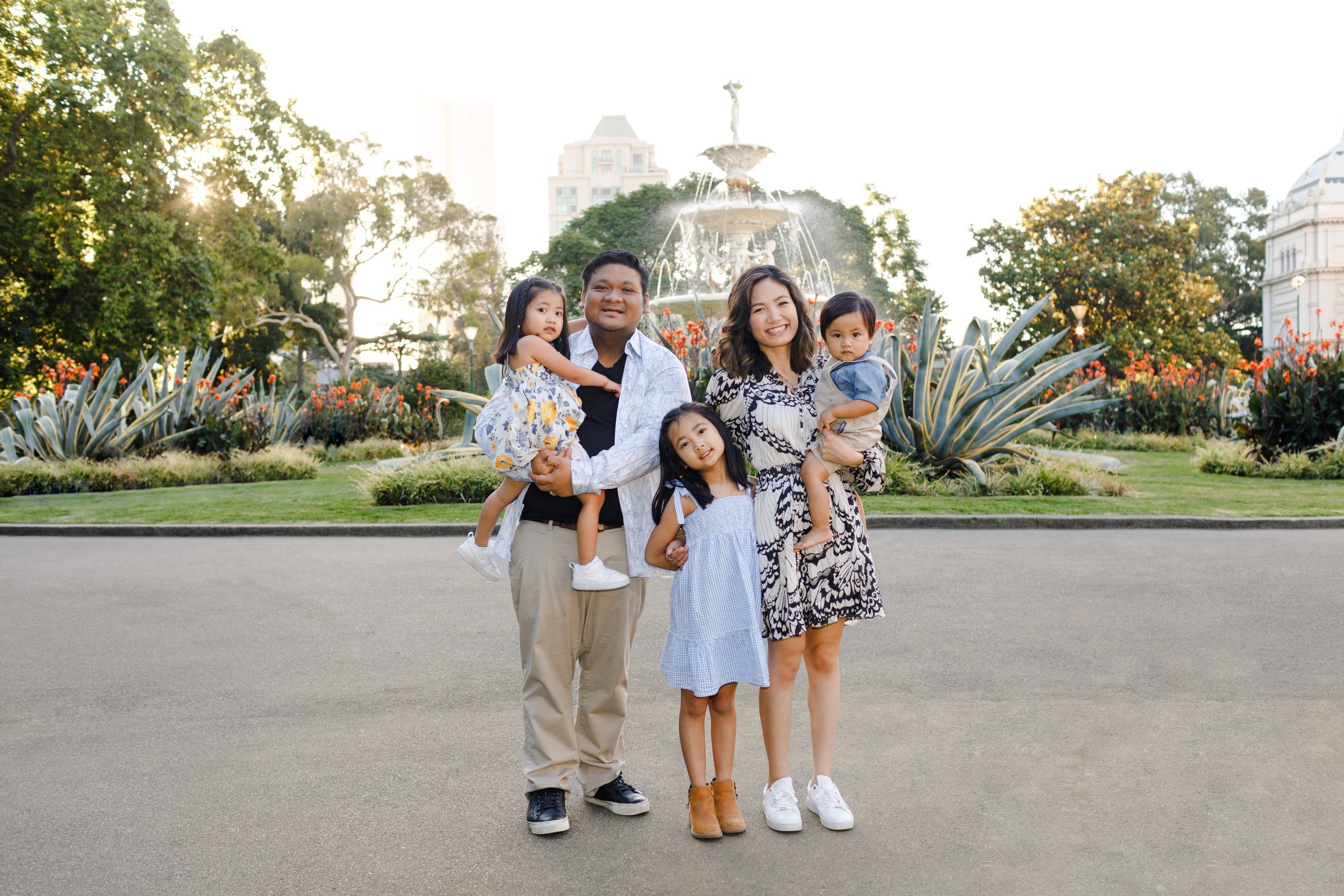 Vania and Marvin with their family, posing outside the Royal Exhibition Building in Melbourne, smiling together.