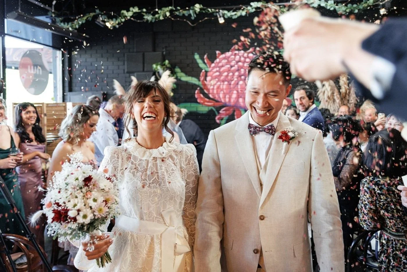 Bec and Nick celebrating under confetti at their wedding at Northside Wines in Northcote, smiling joyfully.