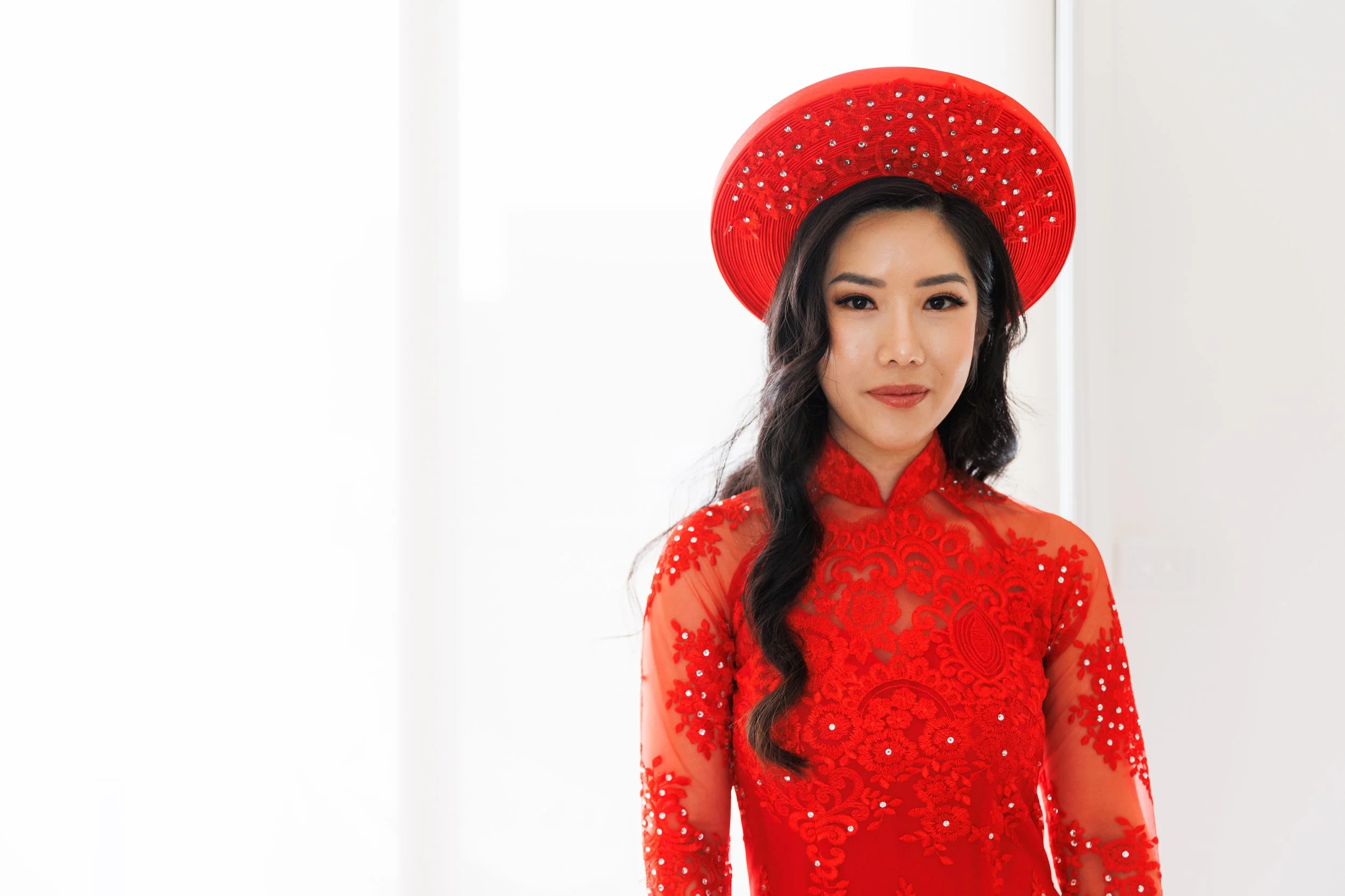 Bride wearing a traditional Vietnamese red áo dài and khăn vấn, posing for a portrait