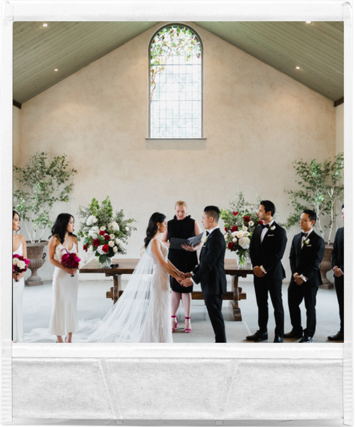 Dishana and Alvin exchanging vows at Stones of the Yarra Valley, with a beautiful floral backdrop and natural light