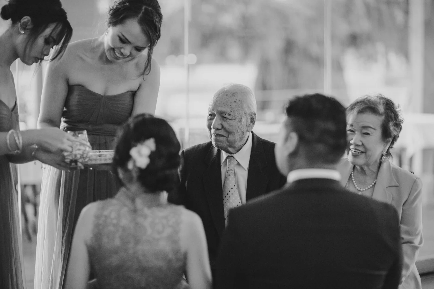 Elders smiling as a couple performs a traditional Chinese tea ceremony, honouring cultural heritage and family bonds