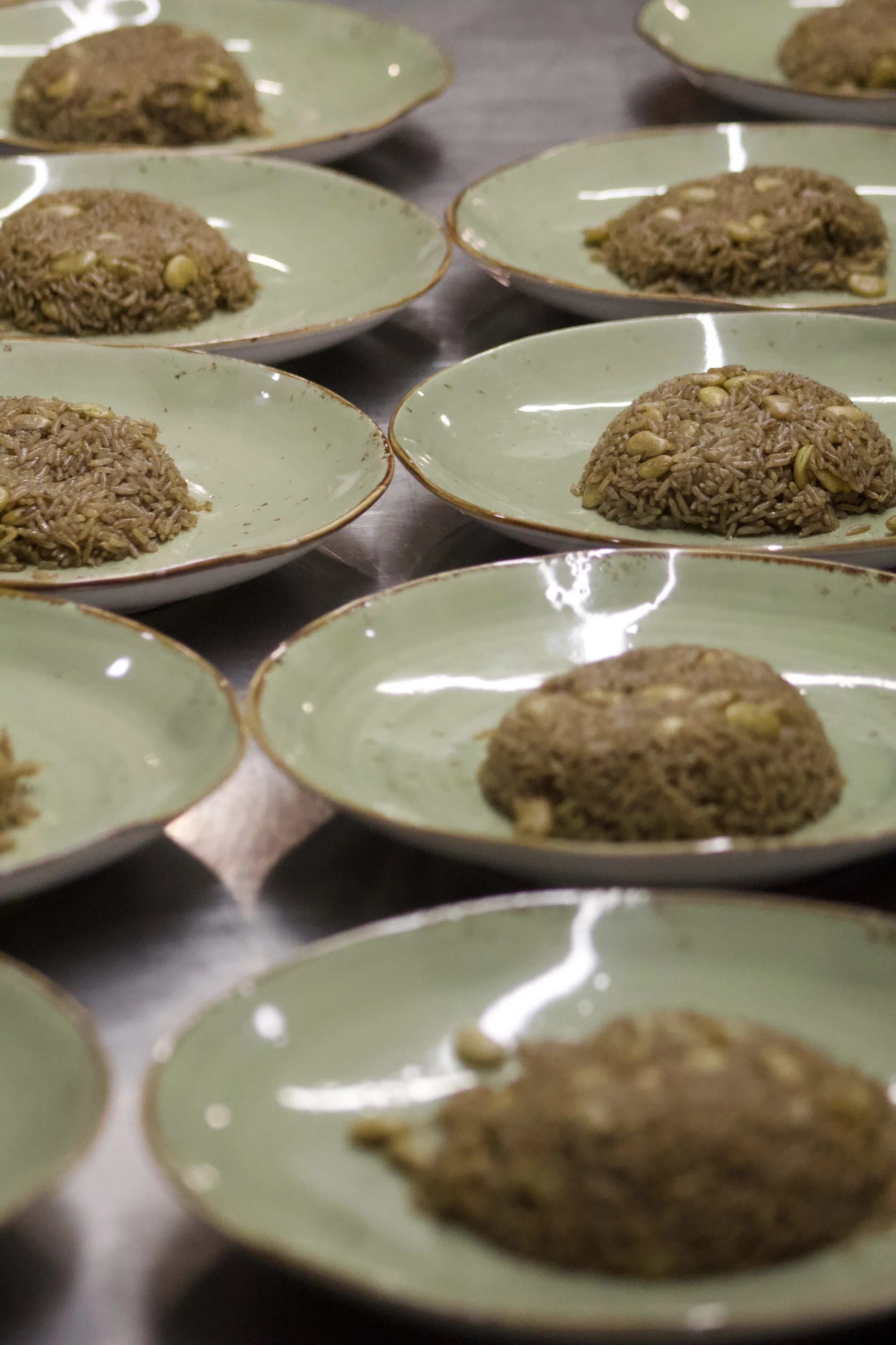 Small green ceramic plates holding servings of Haitian Diri Djondjon and pwa tchous or lima beans.
