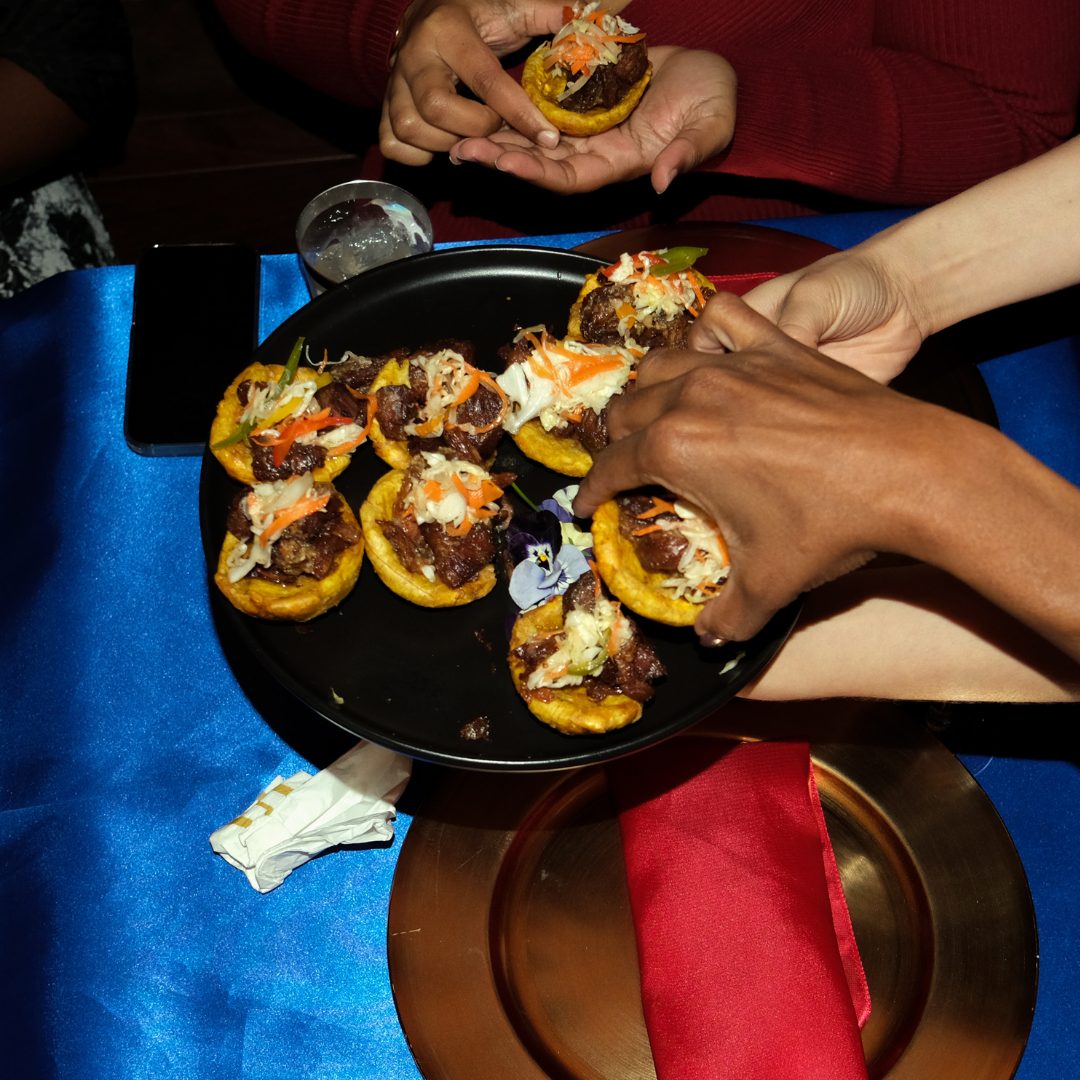 Guests sharing griot plantain cu[s and other Haitian appetizers during a KO Kitchen private dining experience