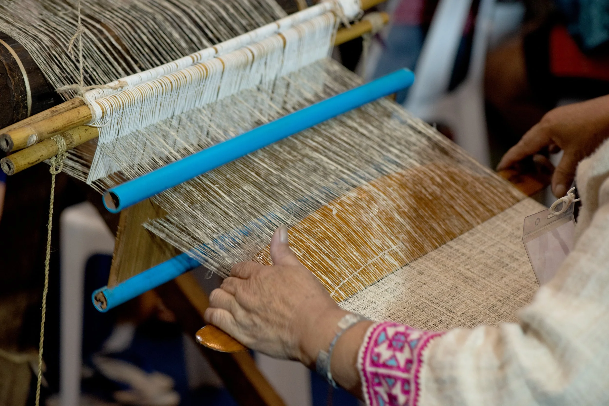 Person weaving on a loom, weaving hemp.