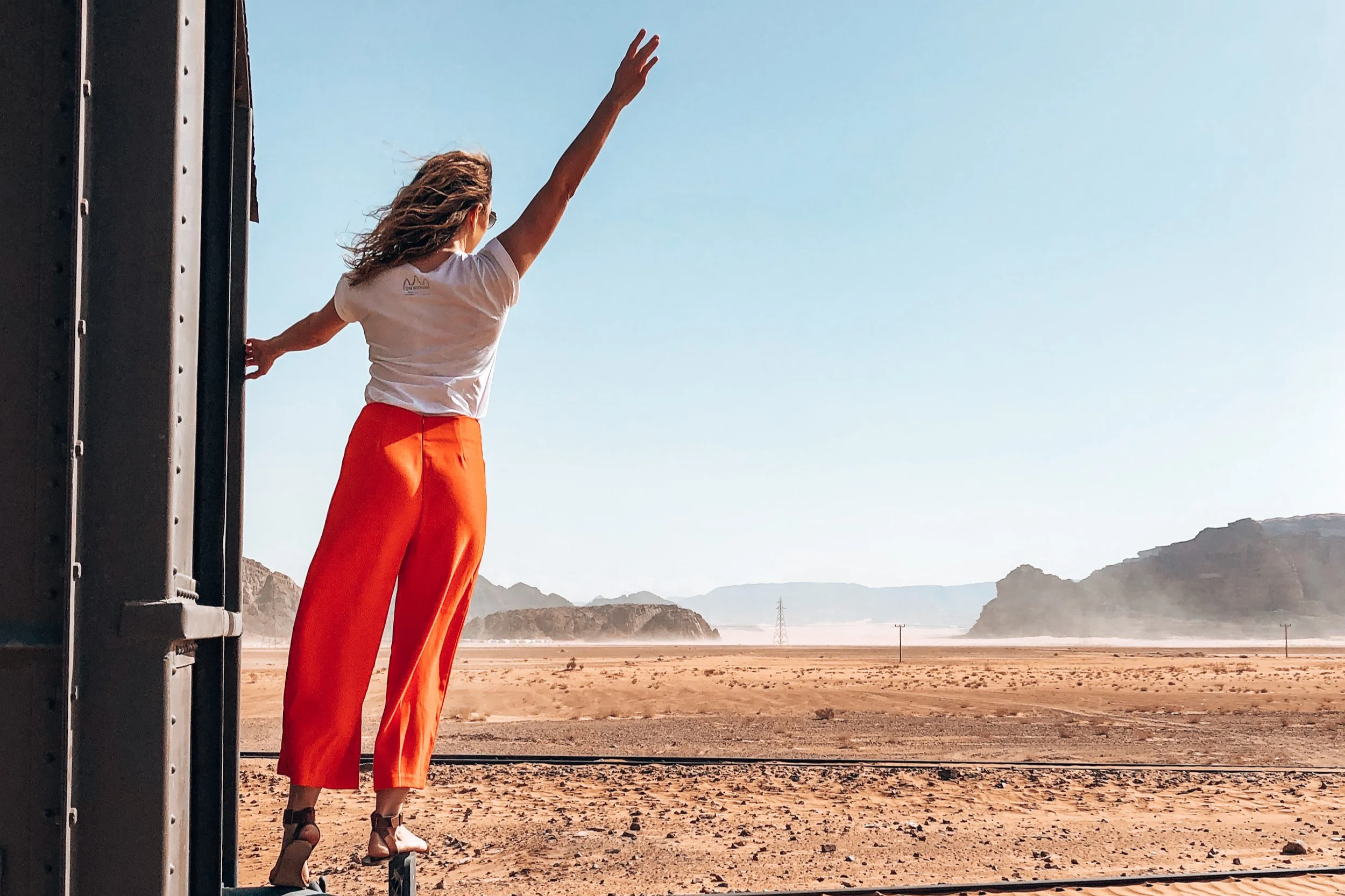 Standing on the back of a train near Wadi Rum in Jordan in the Middle East