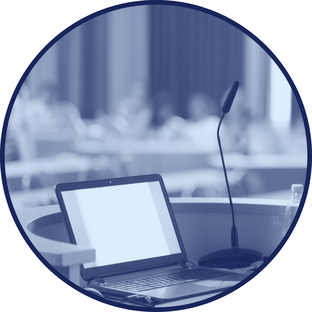 Laptop at a podium in an empty training room prepared for a presentation.