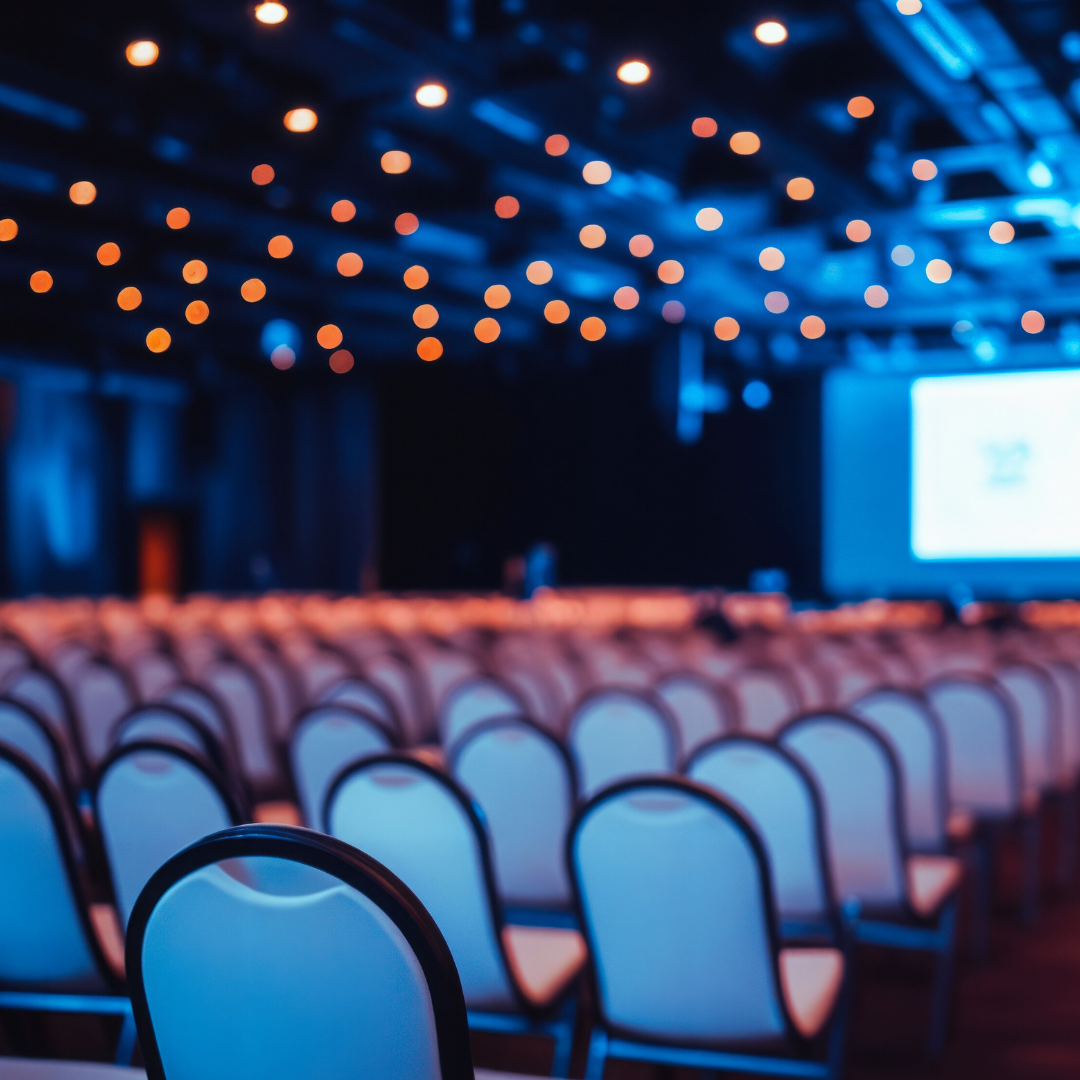 Empty conference room with rows of chairs facing a presentation screen.
