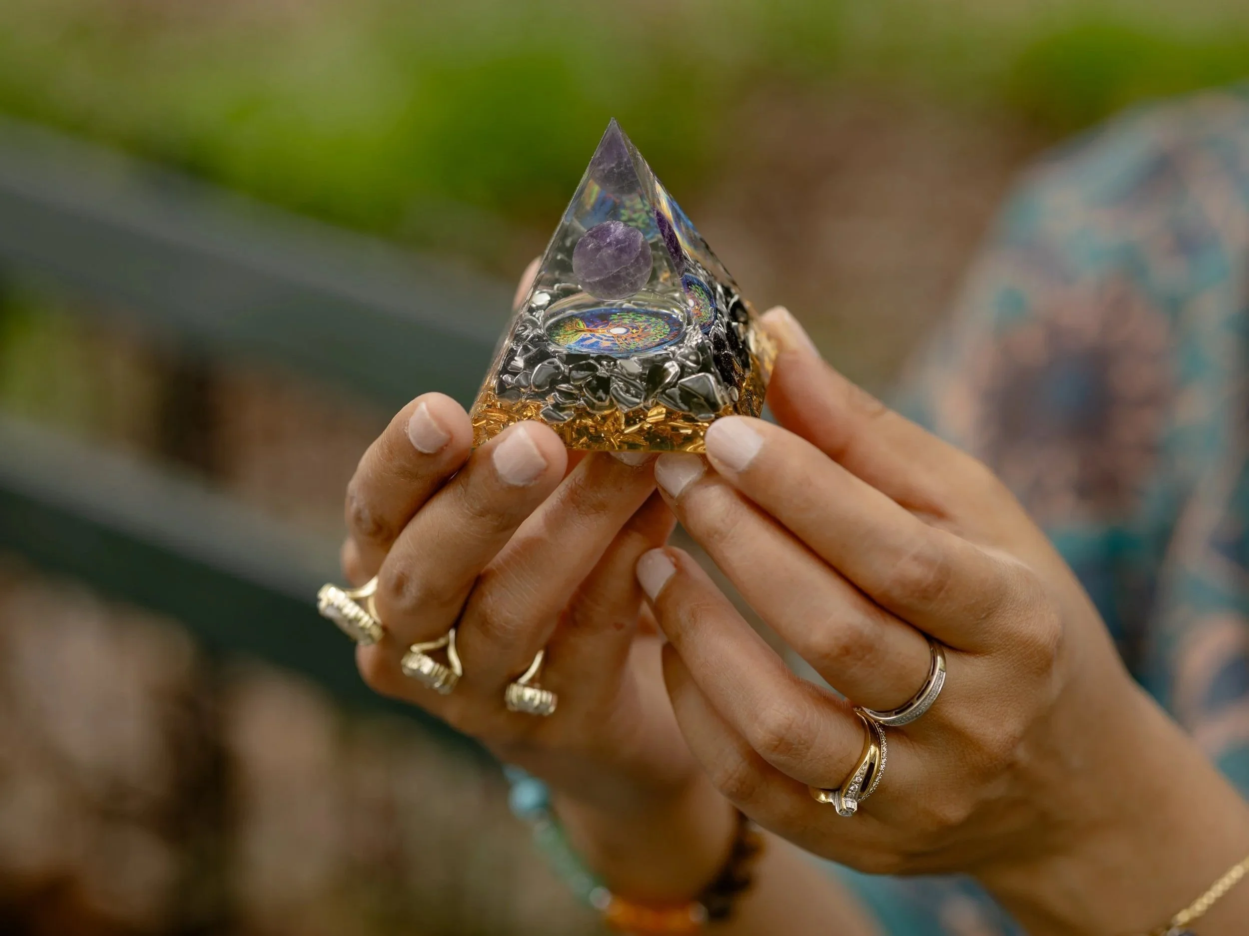 A person holding a small, clear, pyramid-shaped object with a purple sphere and colorful decorative elements inside.