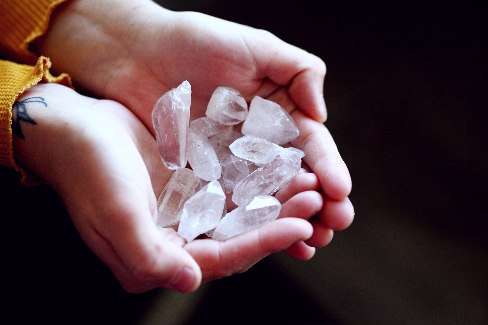 A person's hands holding a collection of clear quartz crystals.