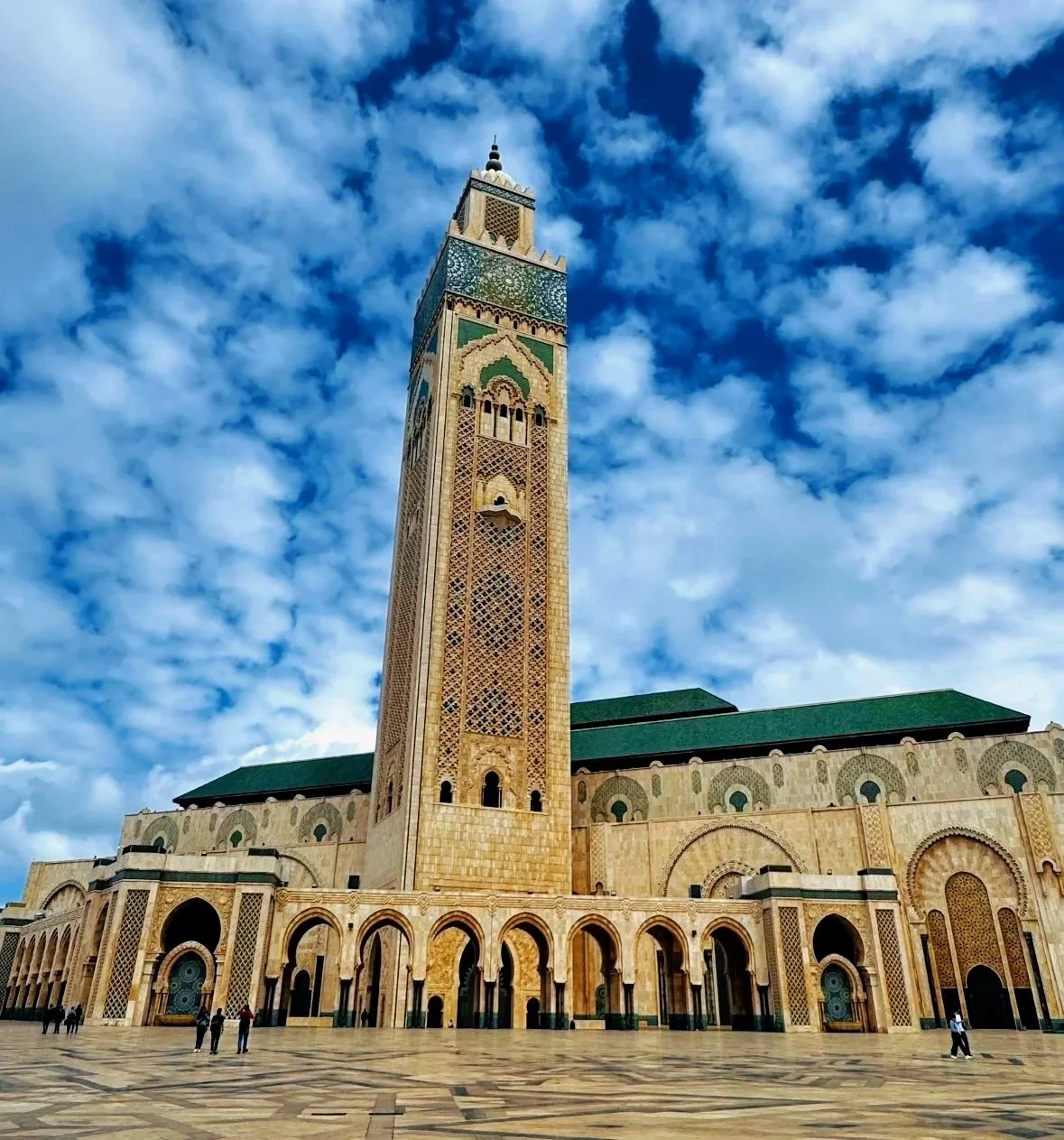 The Kasbah Mosque in Casablanca, Morocco, with its tall minaret, ornate architecture, and a partly cloudy sky in the background.
