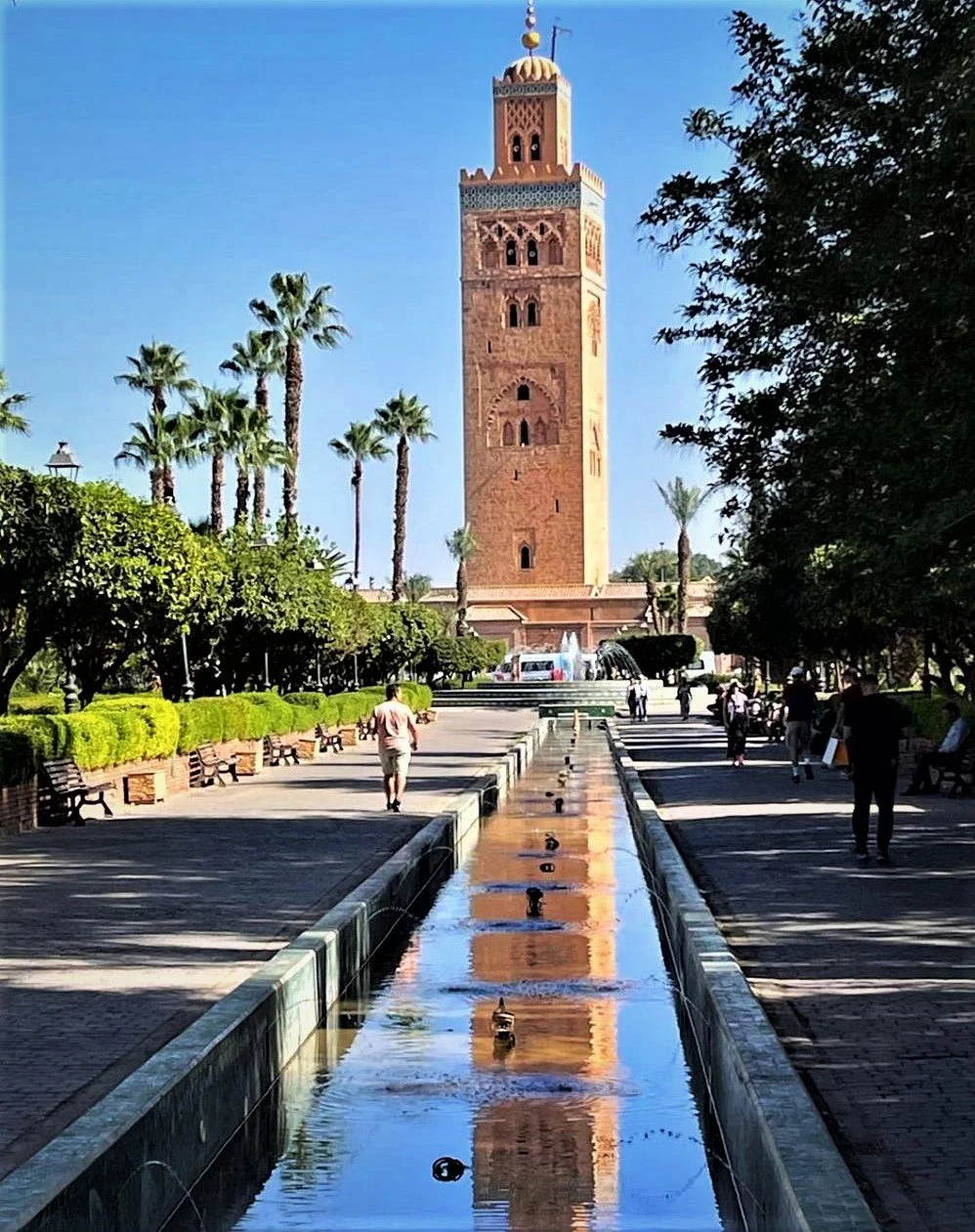 Mesquita Koutoubia em Marrakech com jardins ao redor e piscina de reflexão.