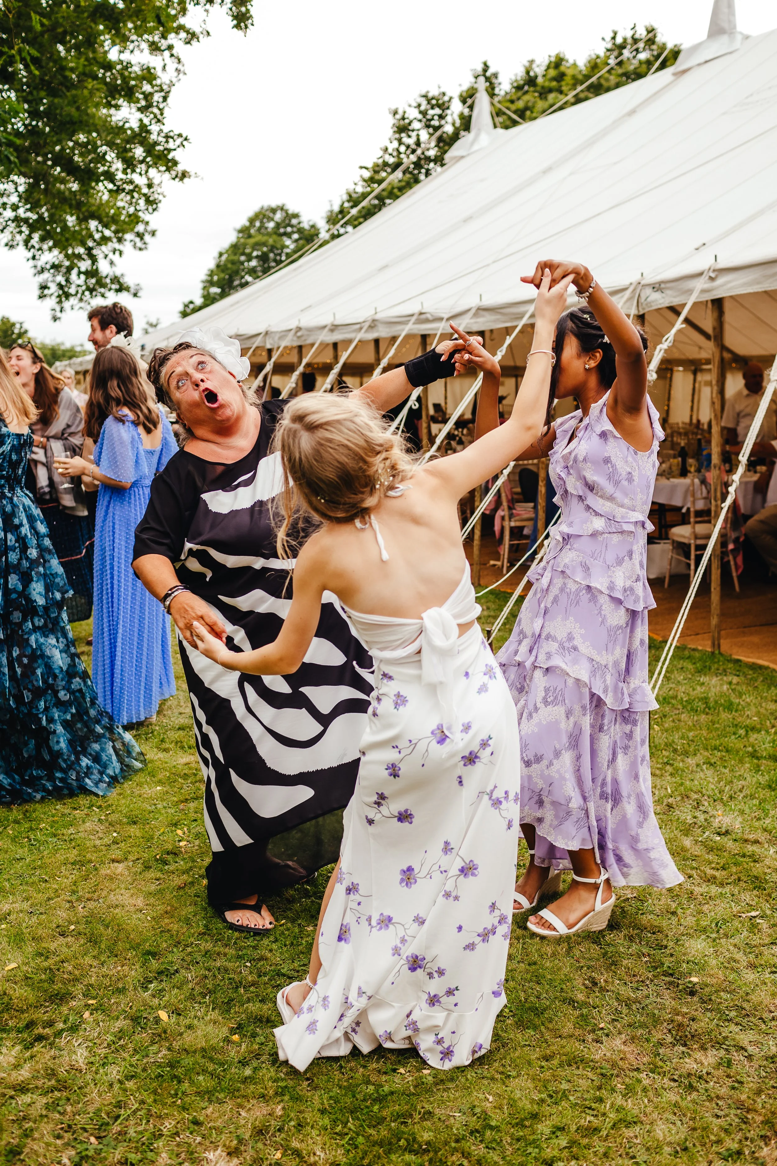 Three wedding guests, in formal dresses, dancing during the drinks reception to Emma Katherine singing
