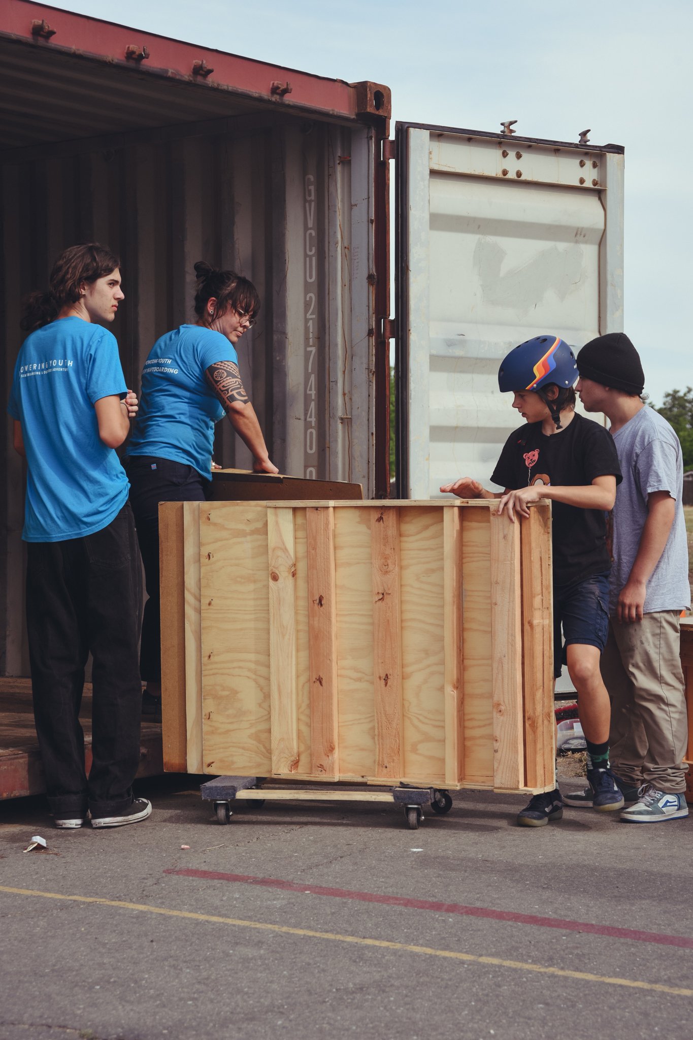 Group of people unloading large wooden crates from a shipping container.
