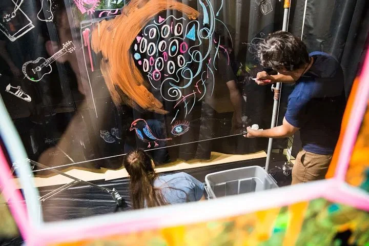 conference volunteers prepare artwork on plexiglass walls.