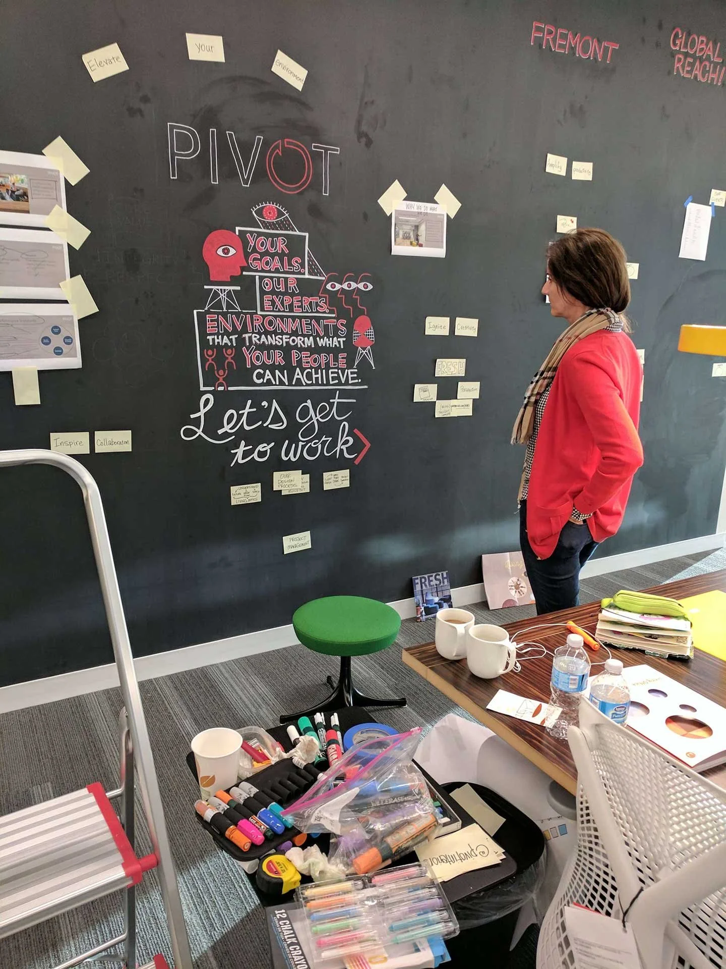Am member of the Pivot Interiors team in a red sweater reviews sticky note and the first drawings titled “Let's get to work!“