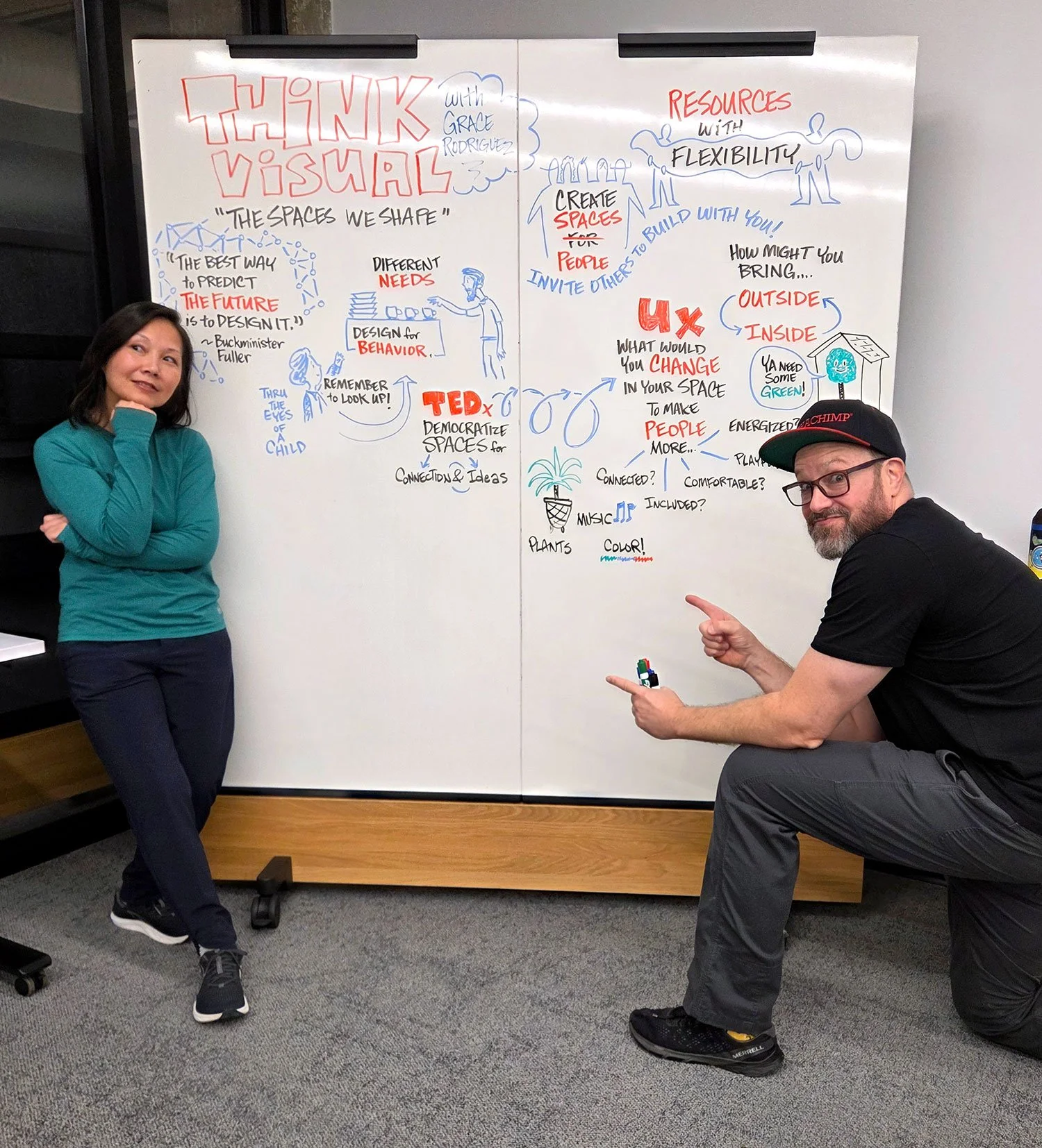 Photo of Grace Rodriguez and Peter Durand posing in front of a whiteboard with visual notes fromThink Visual Meetup in Houston.