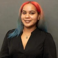 A photo of Isabel Almaguer wearing a black shirt with red and blue hair.