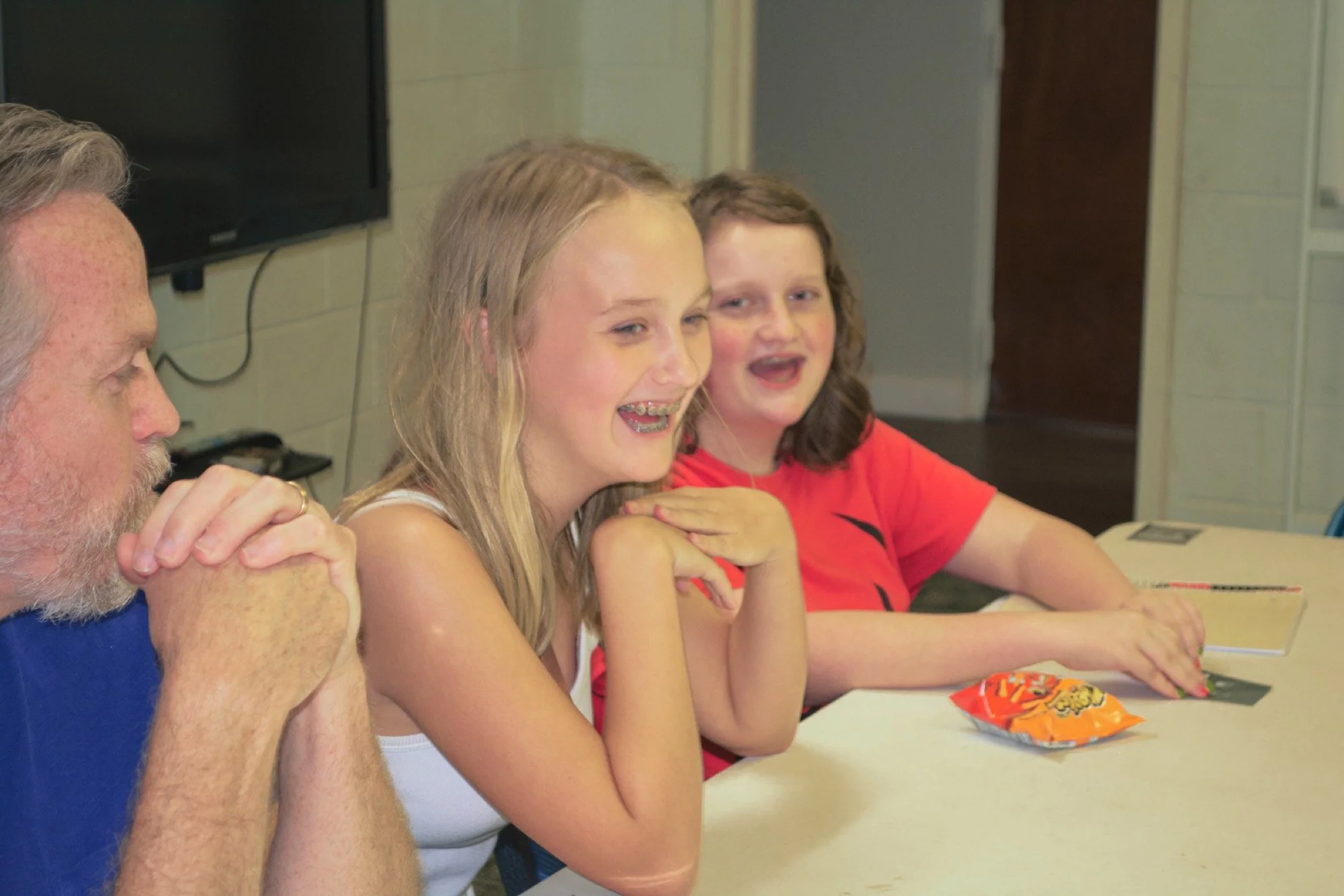 Students and a leader laughing together at a table during a youth night