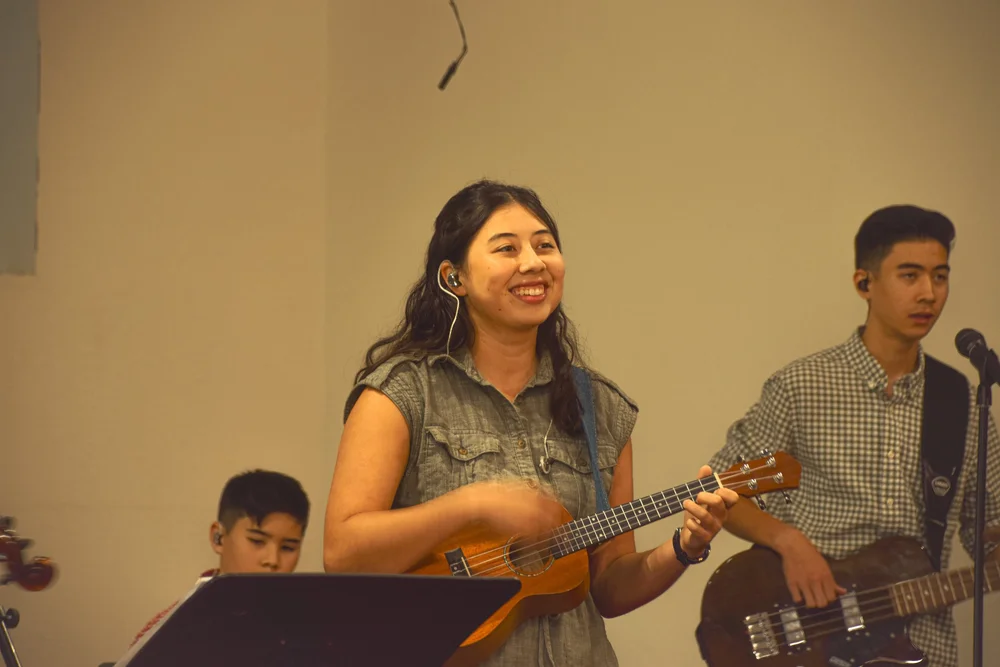 Worship team member smiling while playing ukulele