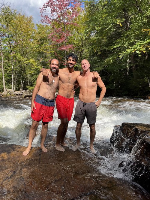 Hassan and clients at a cold river immersion in the fall forest