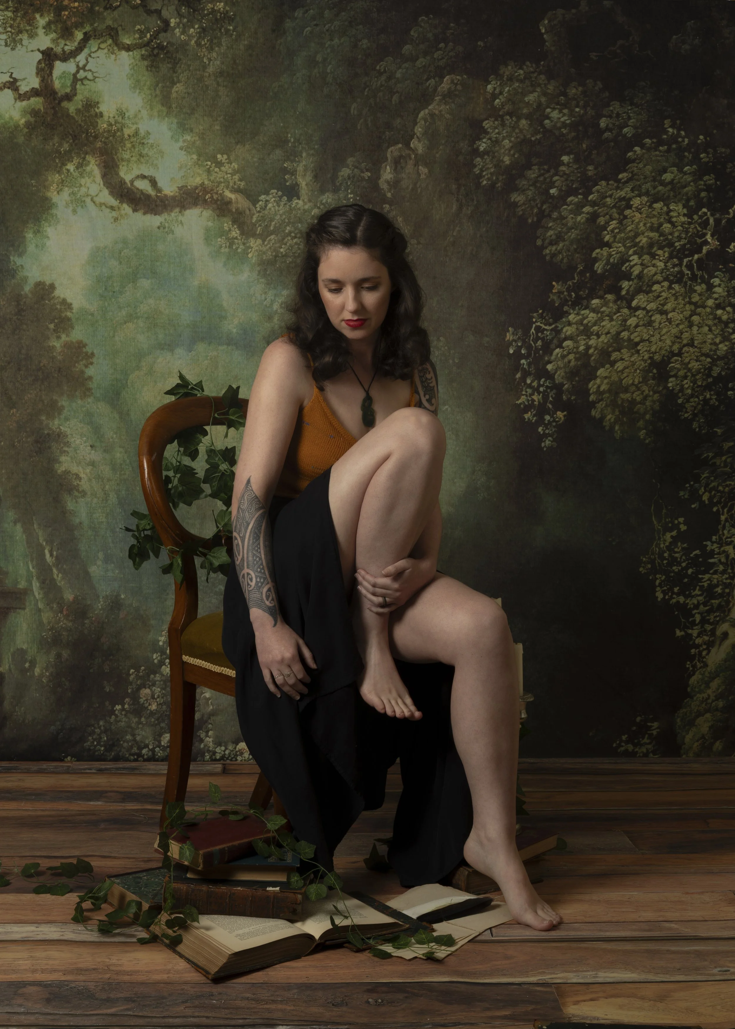 L. M. Woodward sits on an ivy-decorated chair against a forest backdrop.