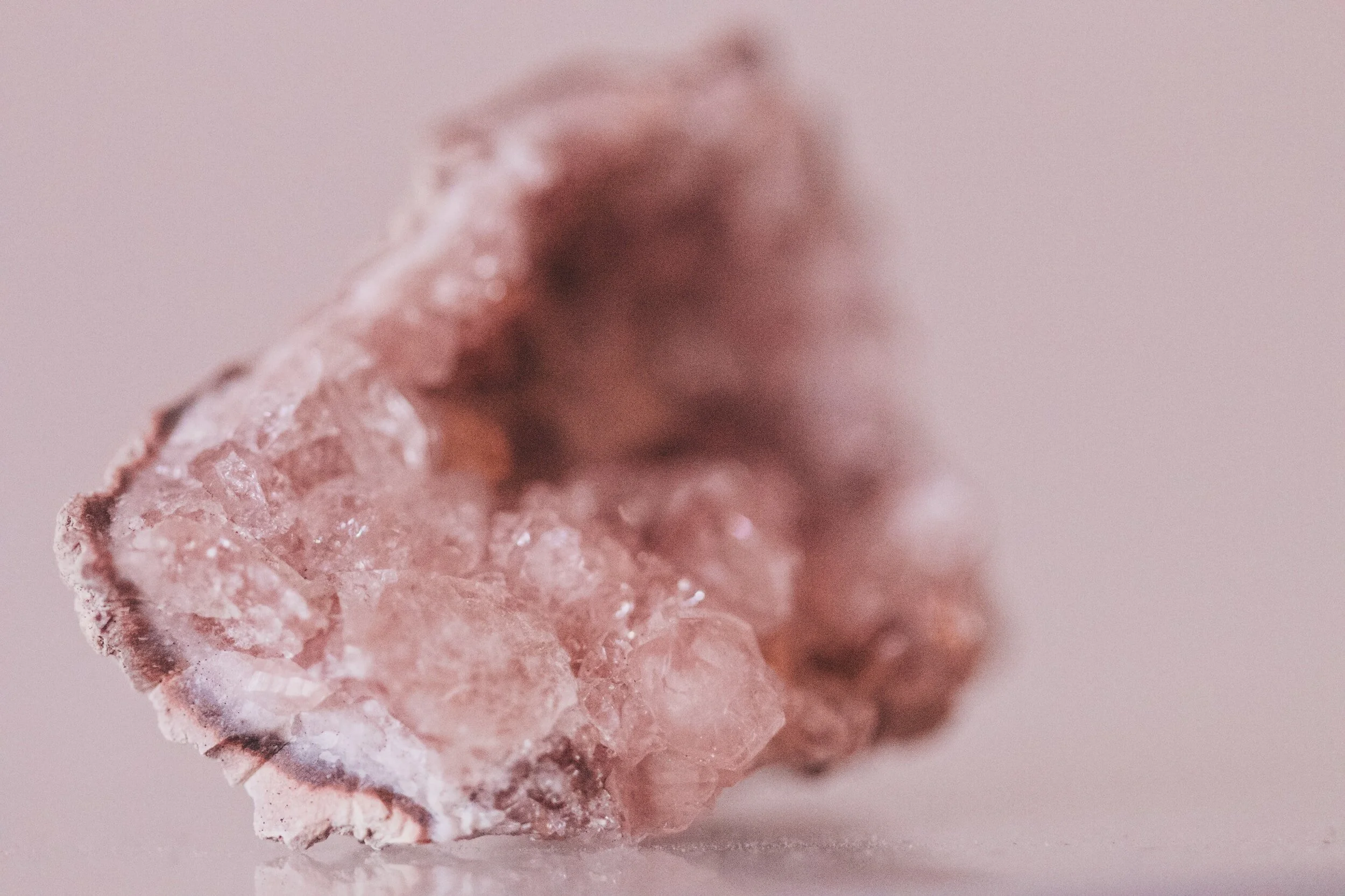Close-up of a pinkish, rough-textured mineral or gemstone with crystalline formations.