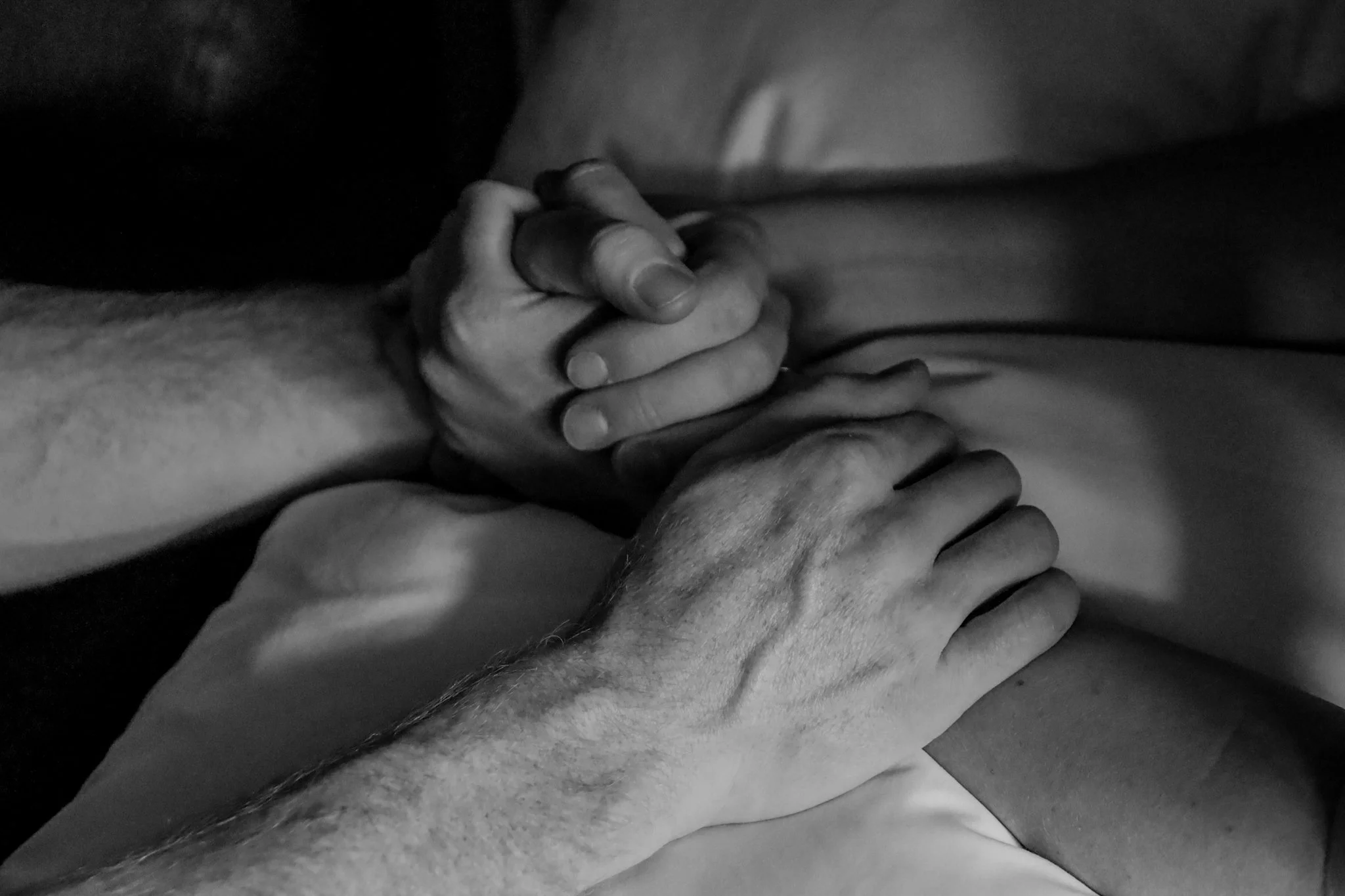 Two people holding hands, one on top of the other, in a close, intimate embrace.