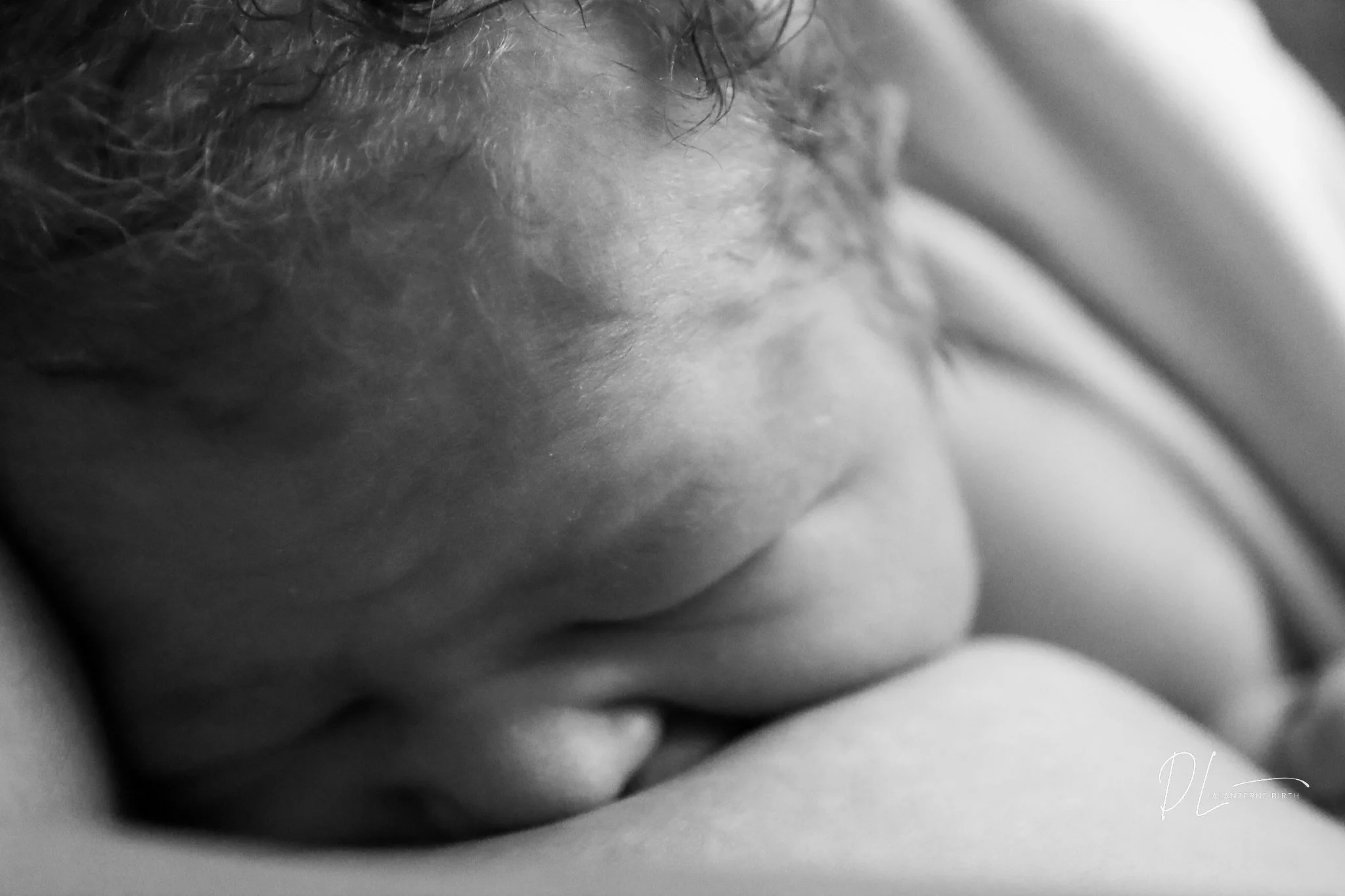 Close-up of a sleeping baby with curly hair resting on a soft surface.