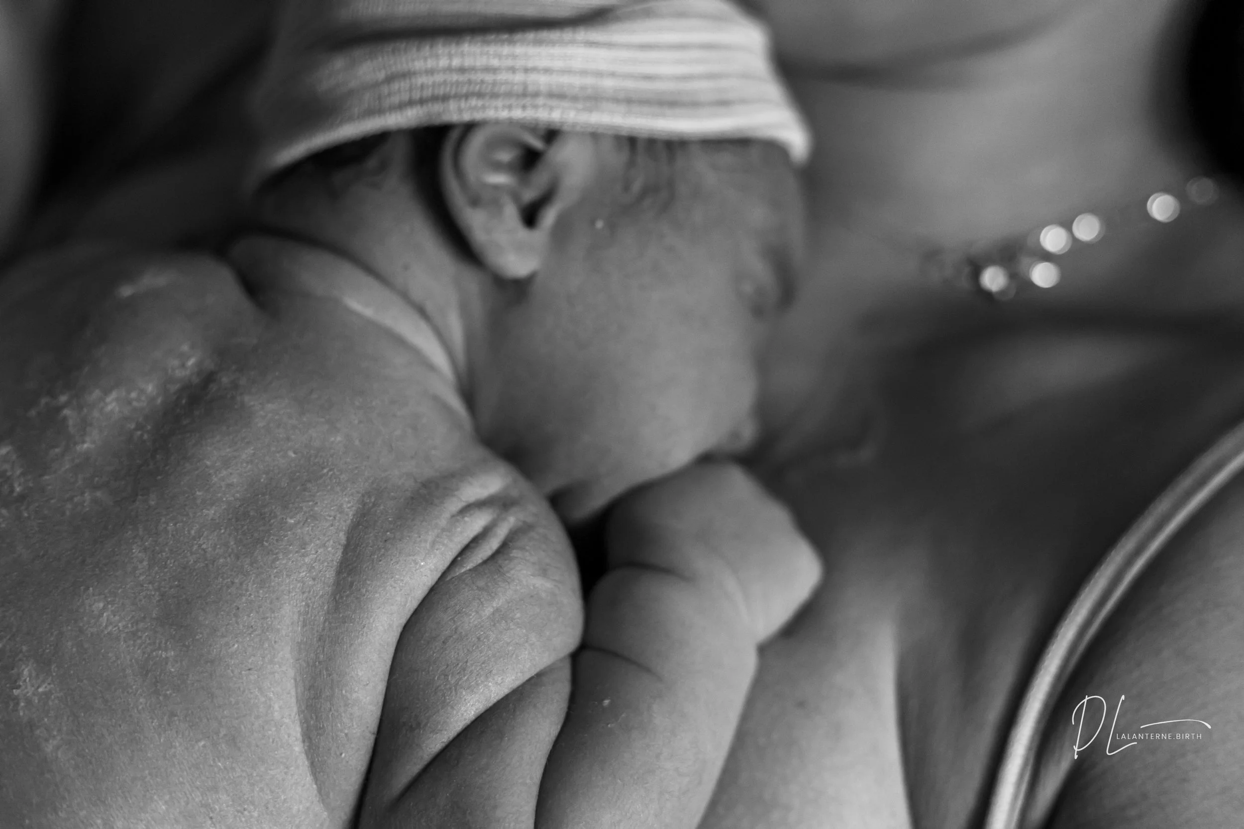 Black and white photo of a woman holding a newborn baby close, both with their eyes closed, in a tender moment.