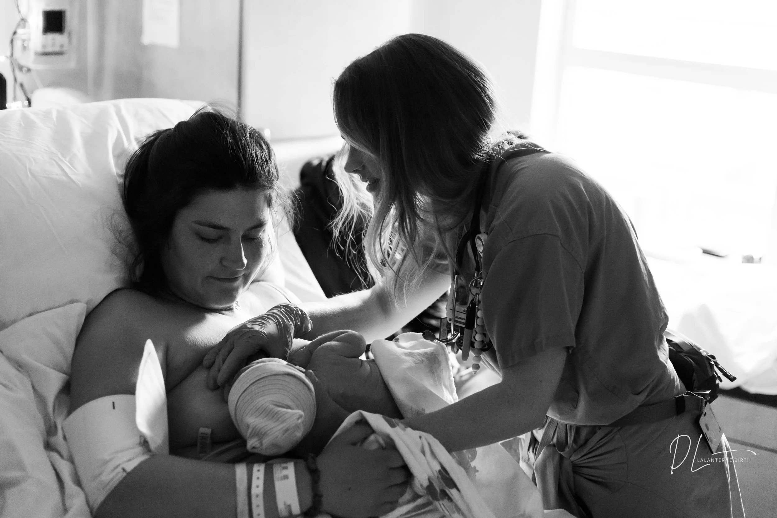 A woman in labor with a doula professional assisting her in a hospital room.