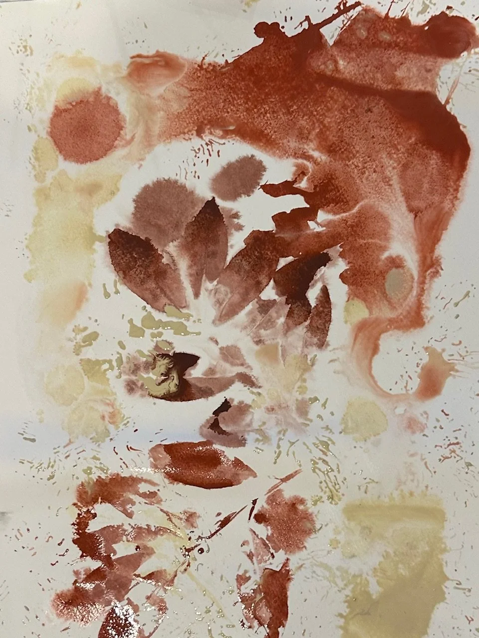 An image of an artwork made with water colour paint and leaves in autumnal tones.