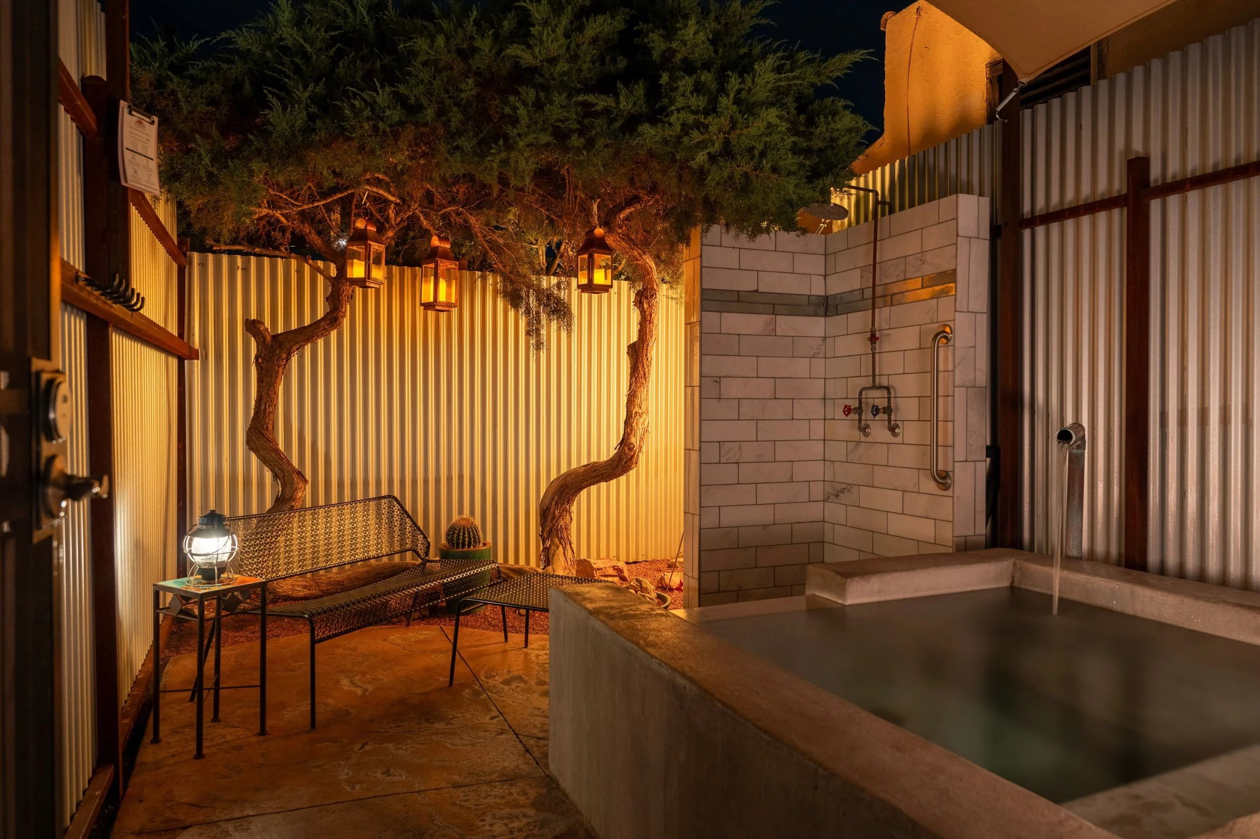 Photo of the Juniper pool at night time with lanterns hanging from the juniper tree