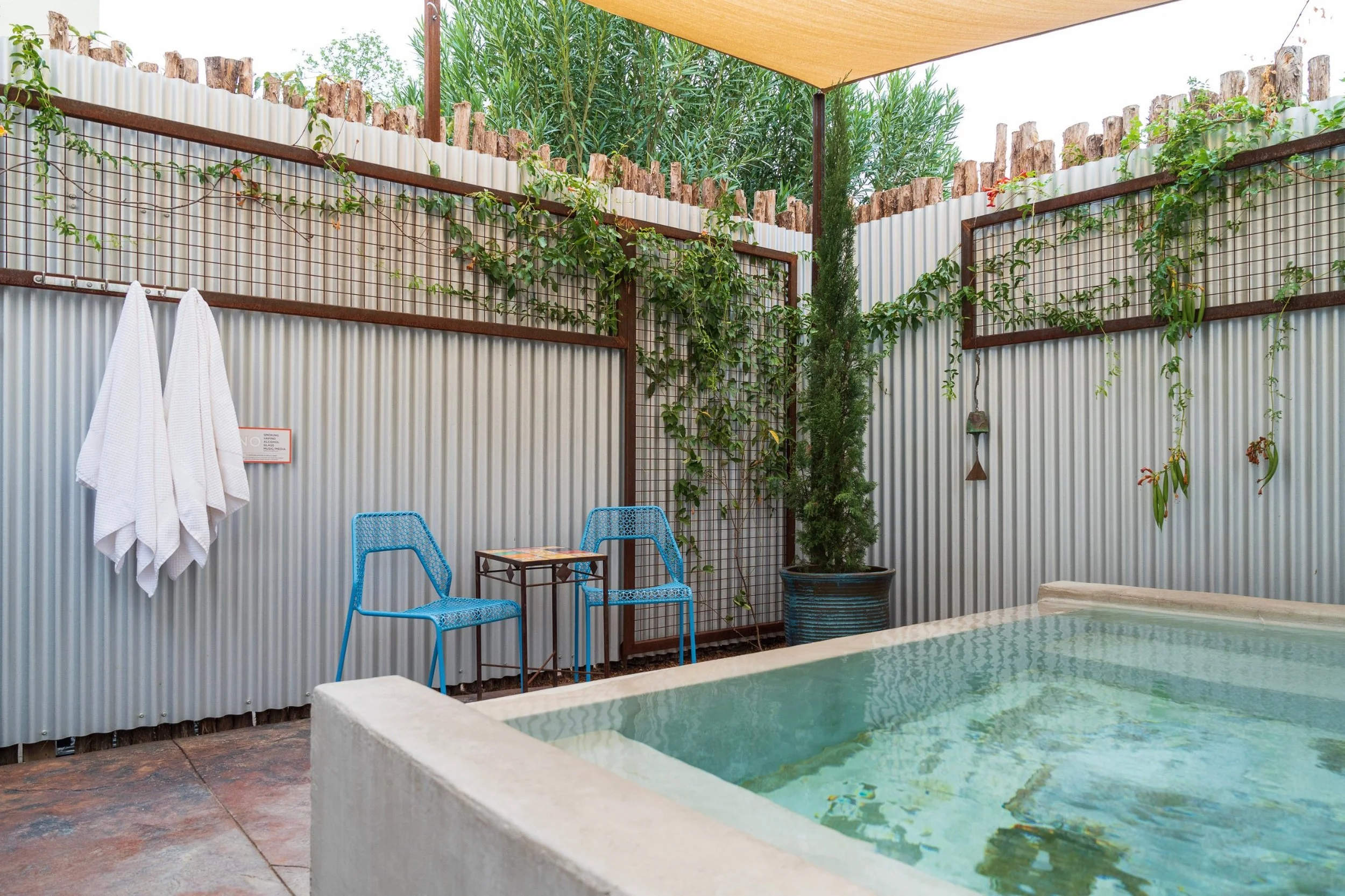 Photo of the Cypress hot springs pool during day time with vines growing on trellises