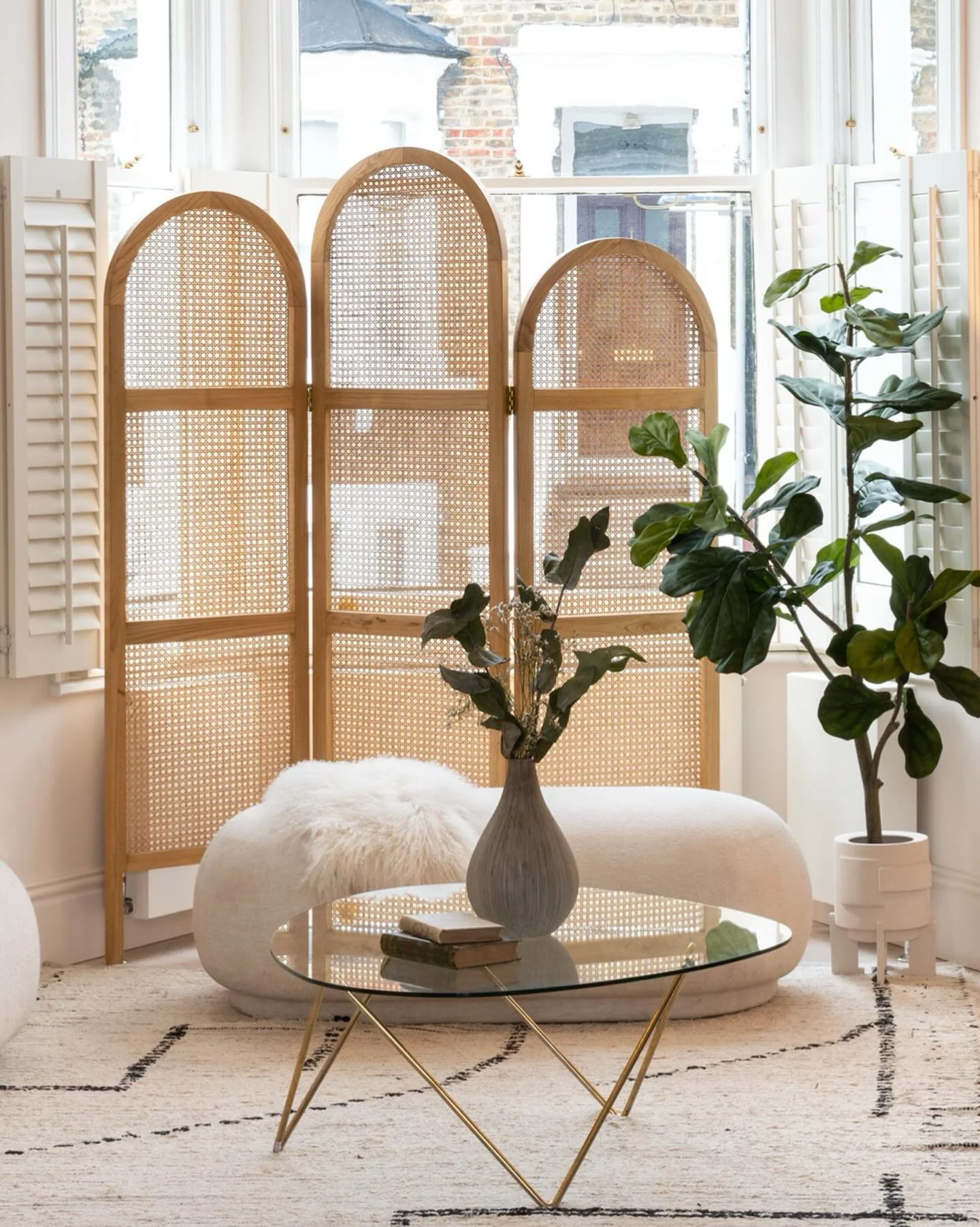 In this Islington living room, the front-facing windows look directly onto the street. A slender timber privacy screen softens the view without blocking natural light, creating a sense of calm in the space.

In front of it, a soft pouffe bench adds f