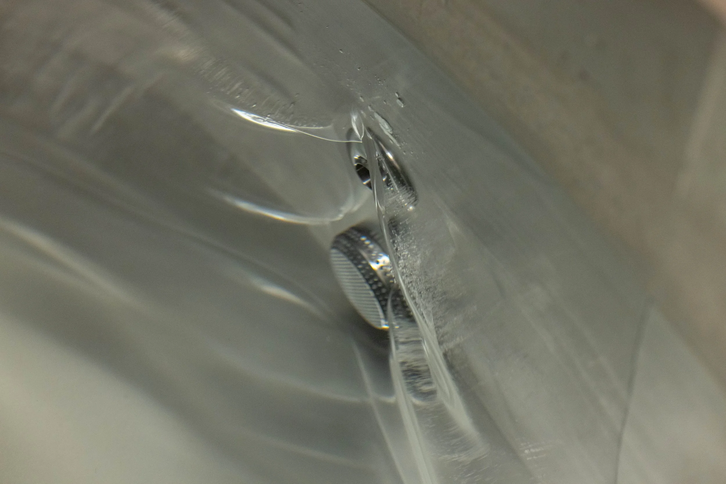 Close-up of a metallic sink drain with water flowing into it.