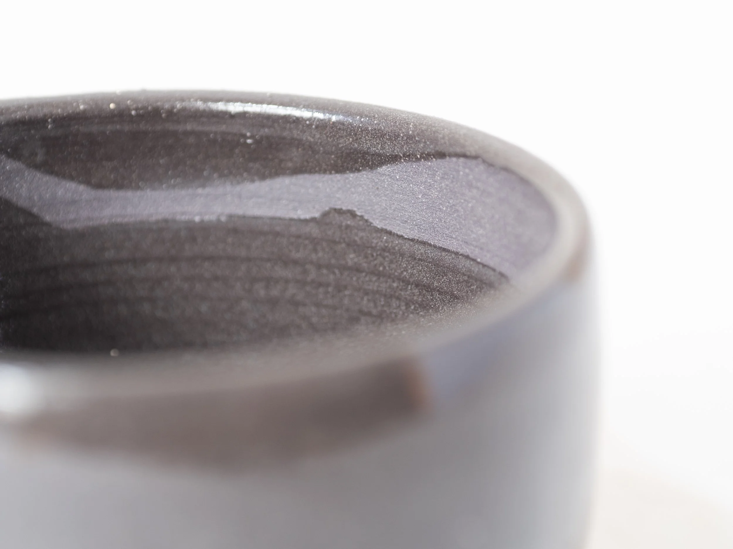 Close-up of a dark, textured, layered surface with fine dust or powder particles.