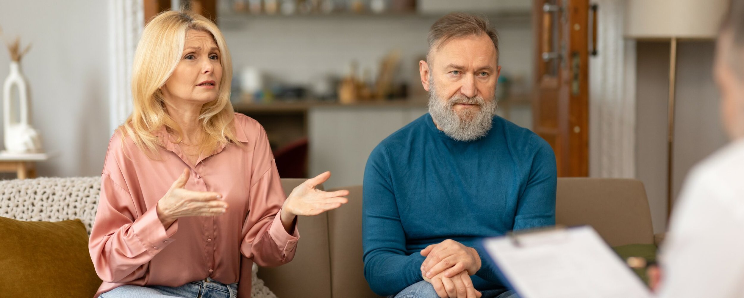 An-unhappy-middle-aged-couple-sits-on-a-couch-talking-to-their-therapist-crop-2-scaled.jpg