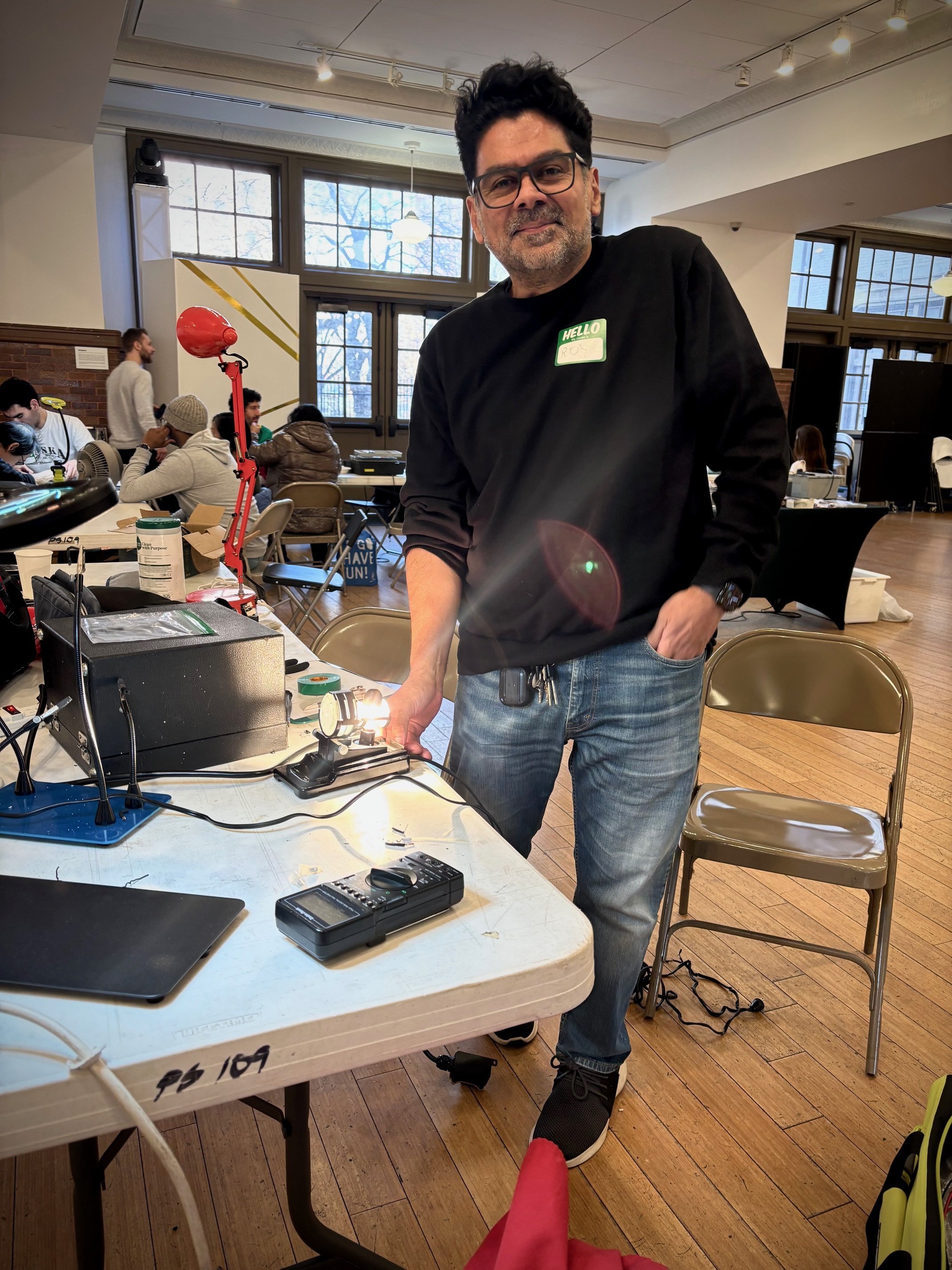 Roy Vanegas, repair cafe el barrio coach and instructor, fixing an old 1930s projector at an event