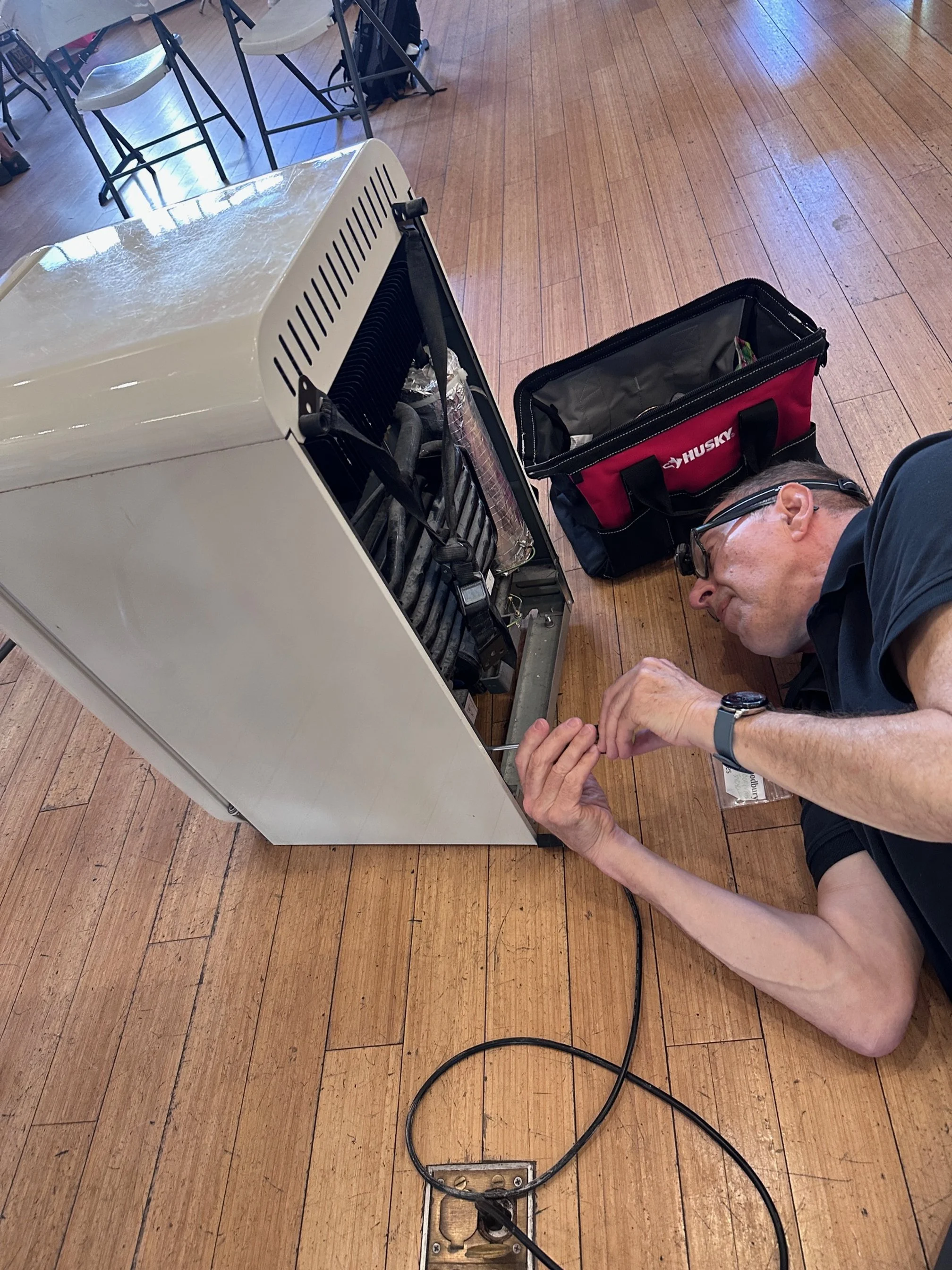 Leland Woodbury, volunteer at Repair Café El Barrio repairing a fridge