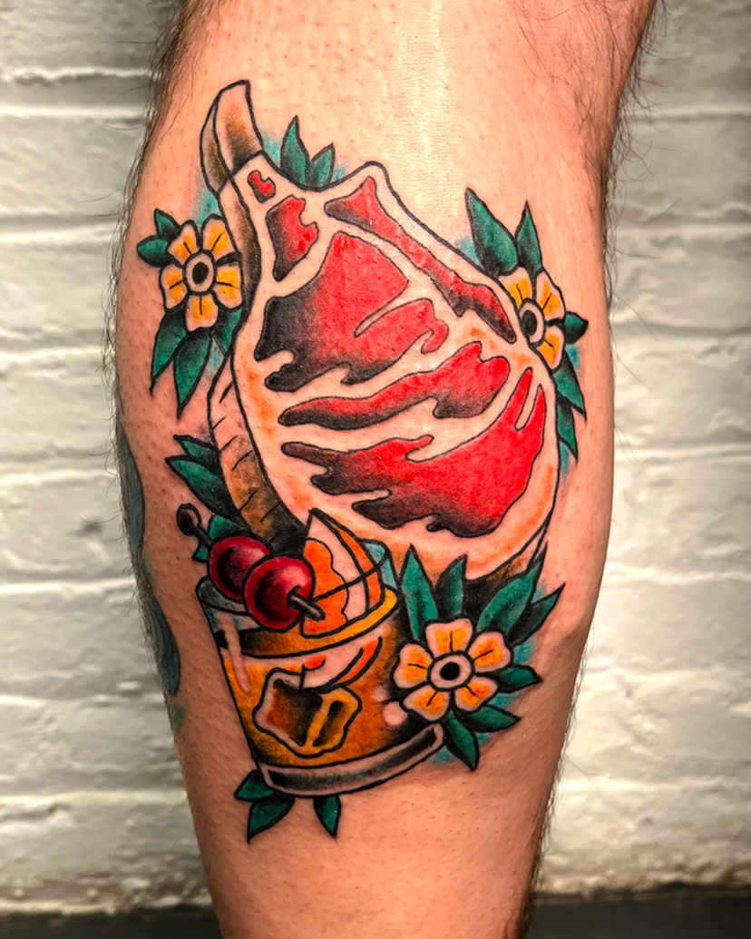 An american traditional tattoo of a raw steak with an old fashion cocktail and some small flowers around it