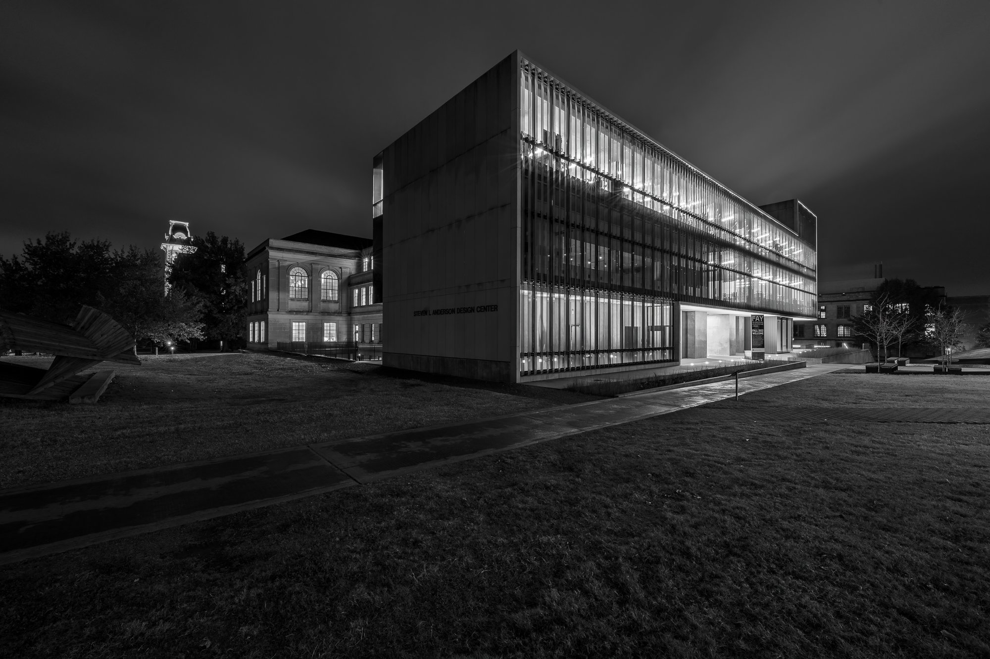 Night view of a modern building with large windows, labeled "Steven L. Anderson Design Center," surrounded by a grassy area and illuminated in LED lights.