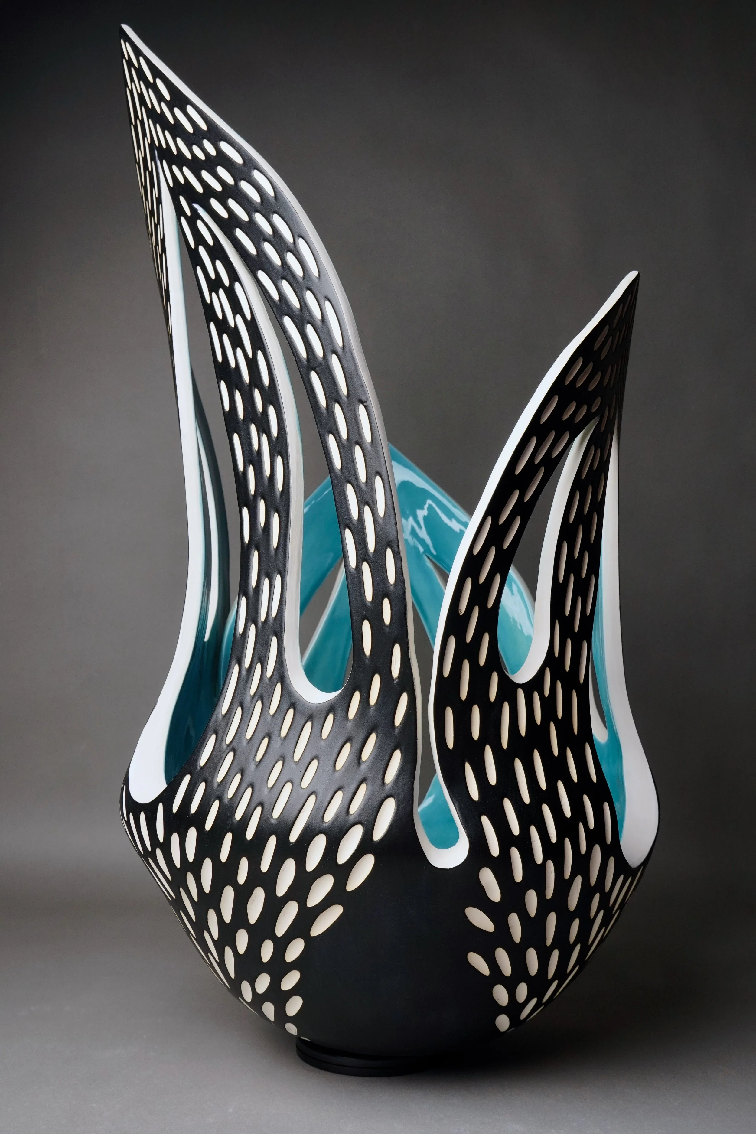Modern sculptural art piece with black and white perforated organic shapes against a plain background.