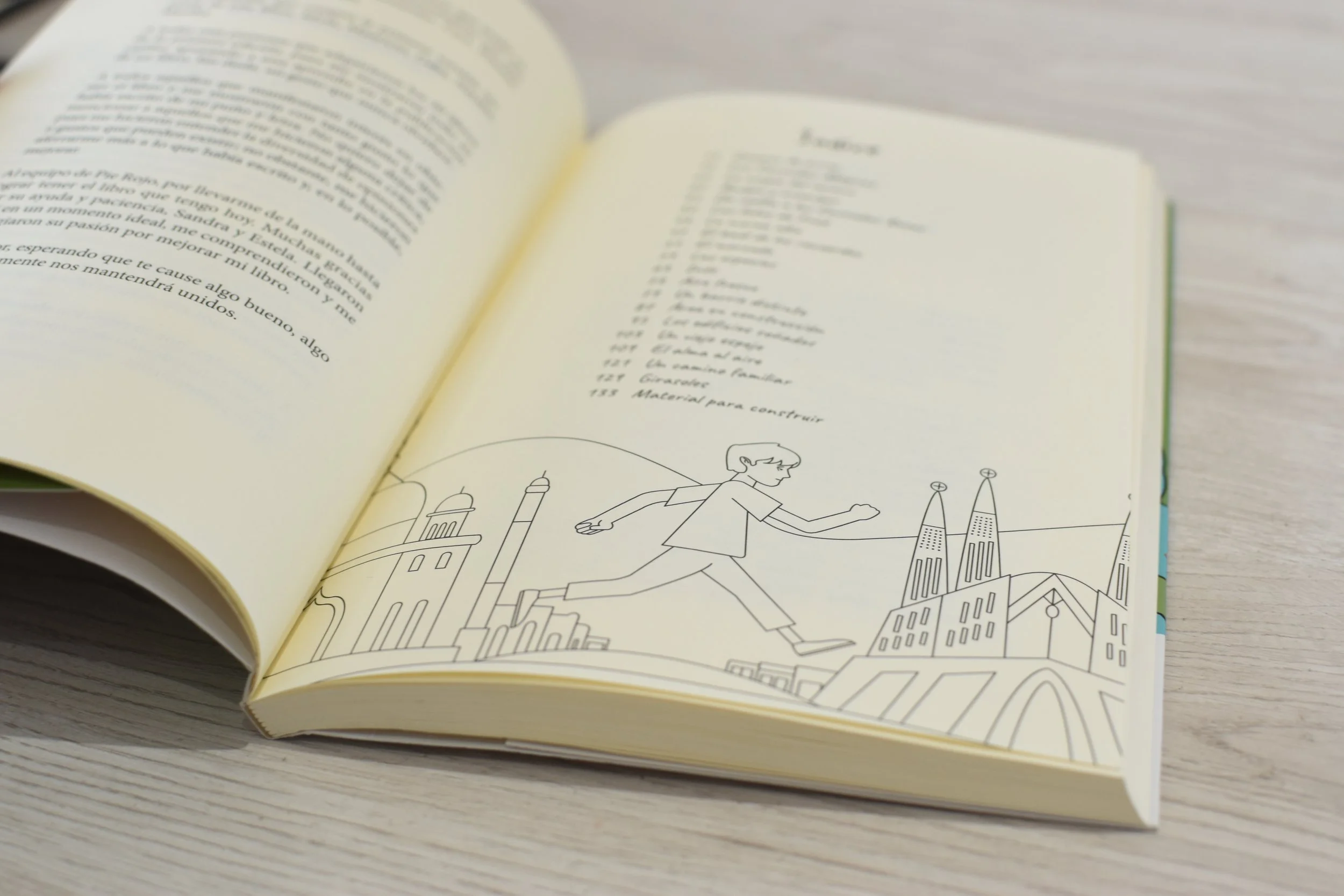 Libro abierto con dibujo lineal de una persona corriendo en un paisaje urbano con edificios famosos de Barcelona, como la Sagrada Familia y la Torre Agbar, en la esquina inferior derecha.