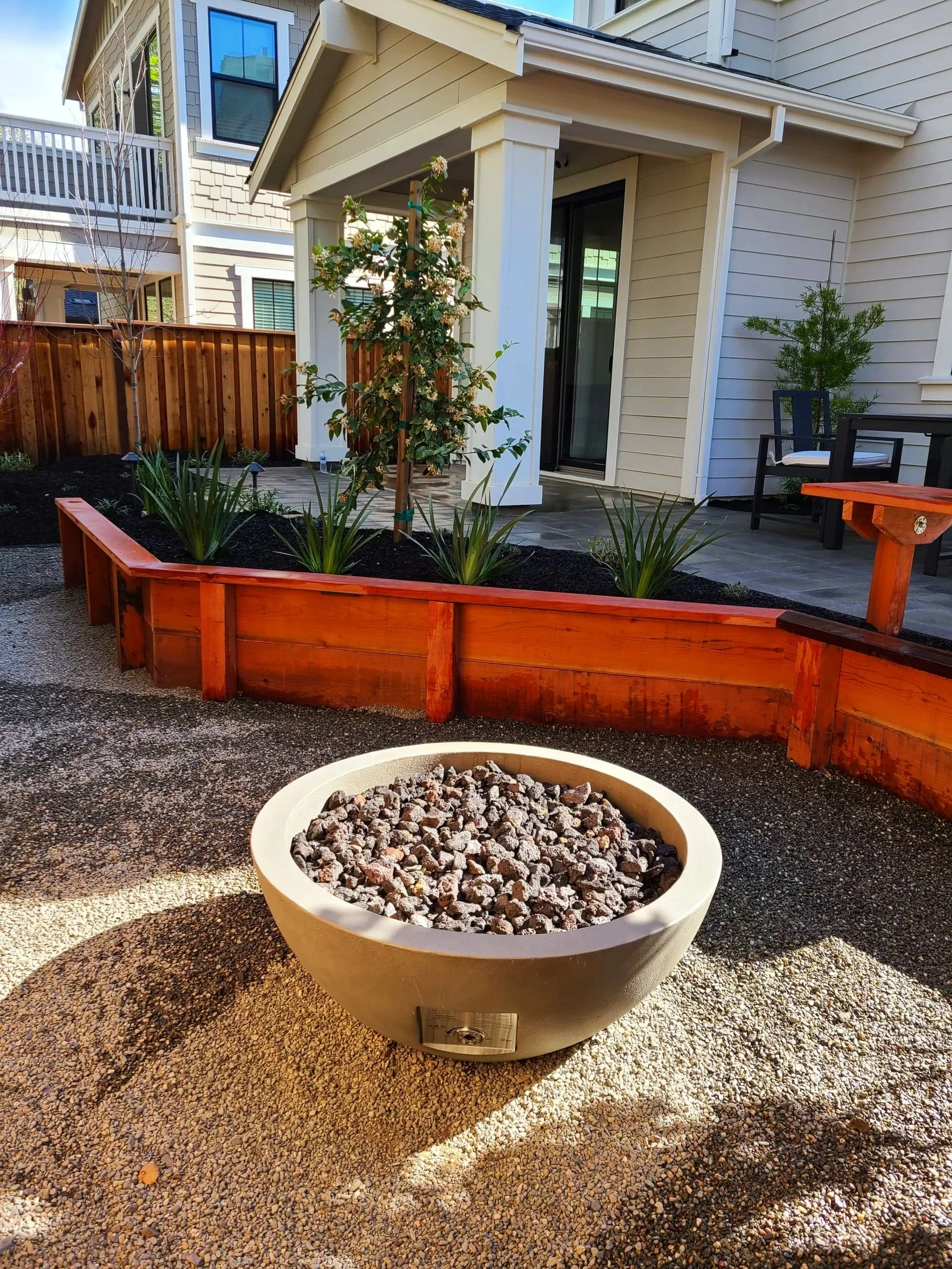 Backyard with raised wooden planter beds and bowl shaped concrete gas fireplace