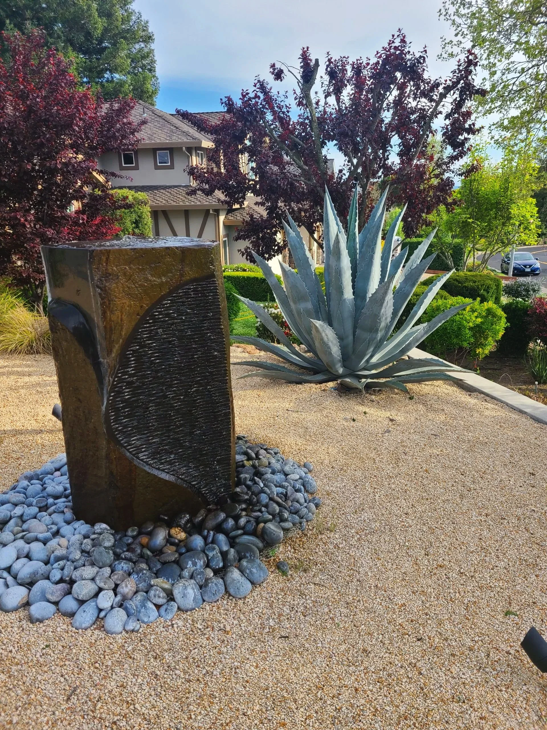 Sonoma backyard with small gravel and large concrete rectangular fountain surrounded by large round stones