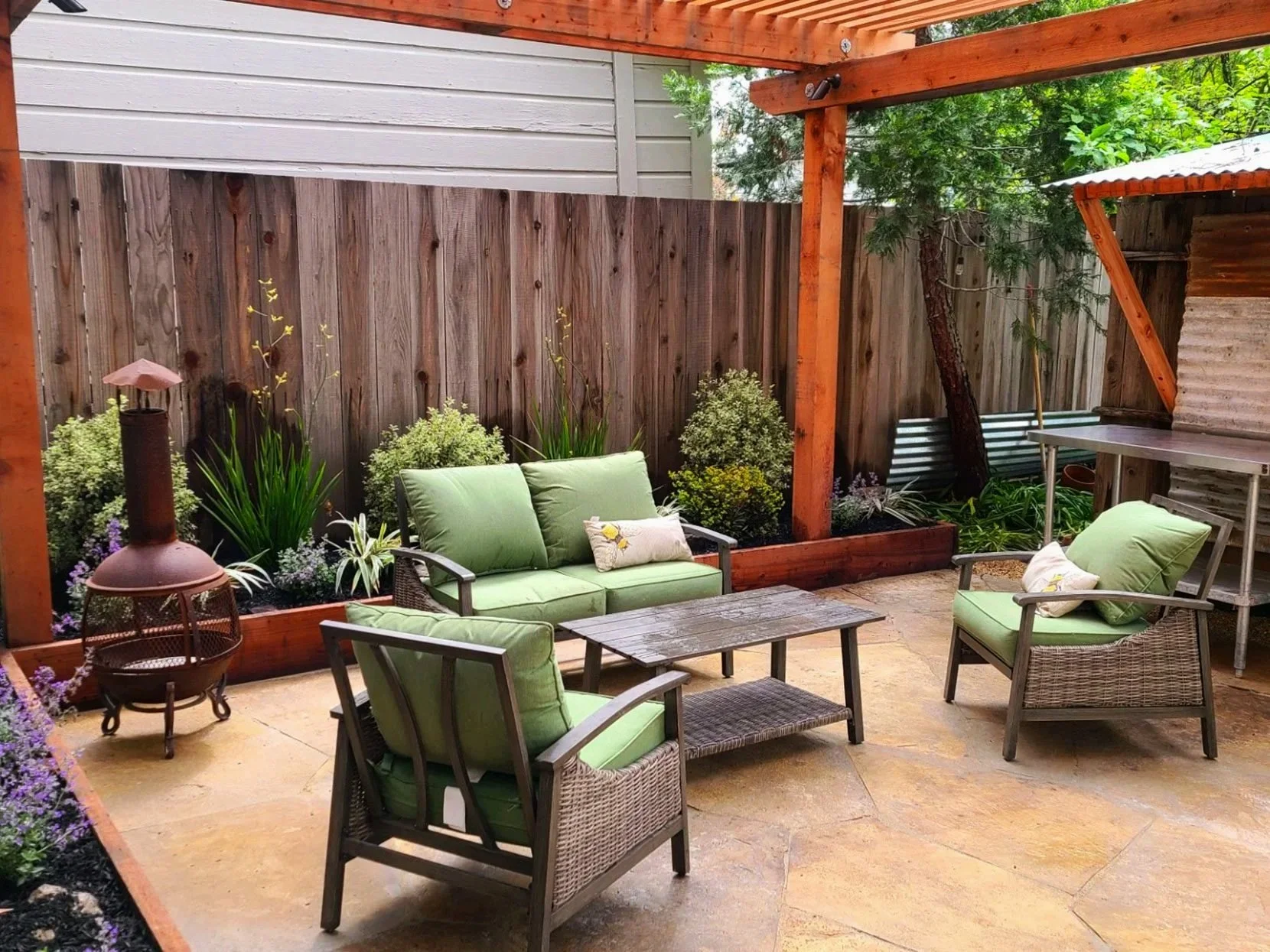Pavered patio with wood raised garden bed and wood fence and pergola