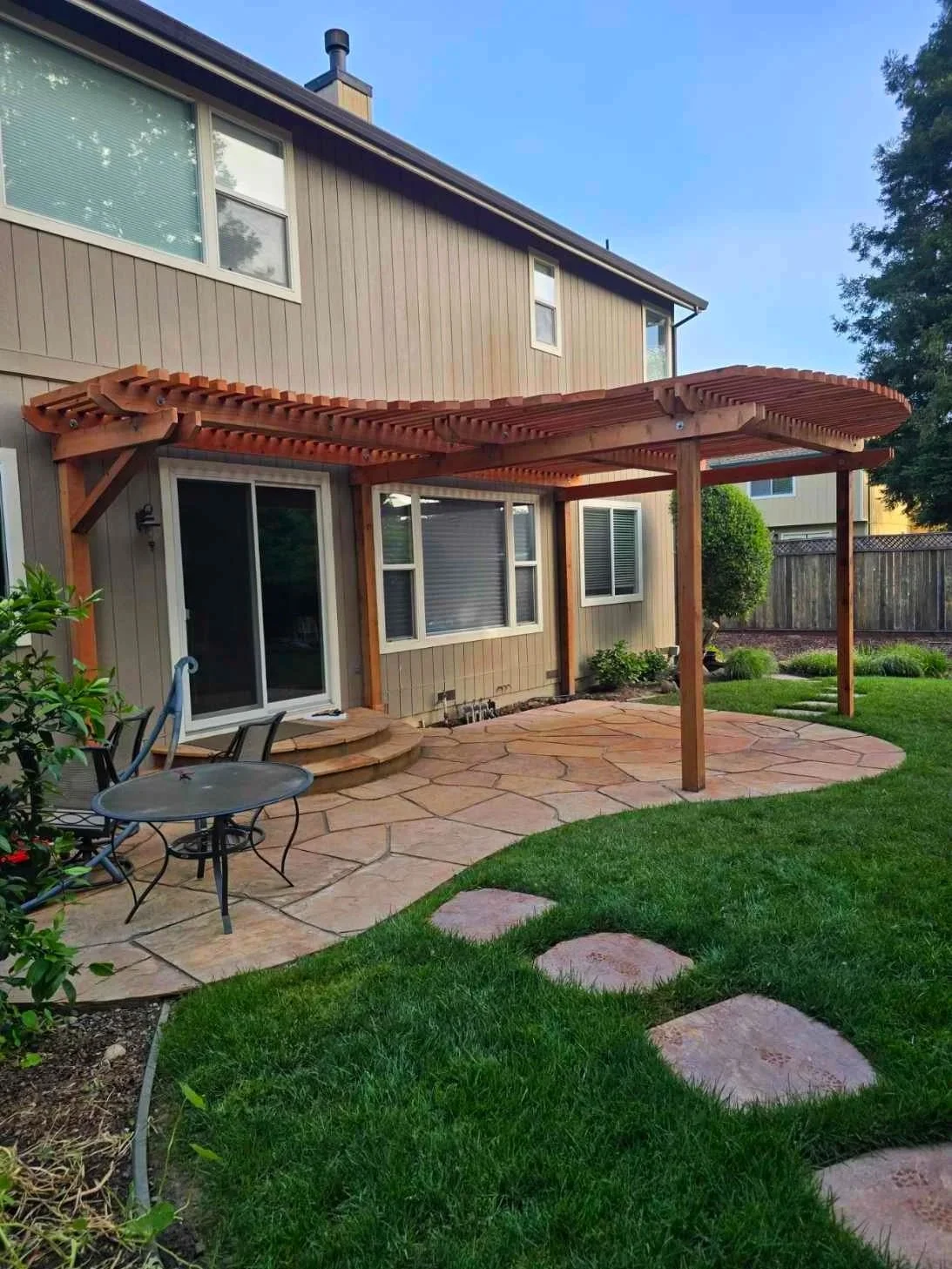 Pavered back patio with newly installed slated wood pergola