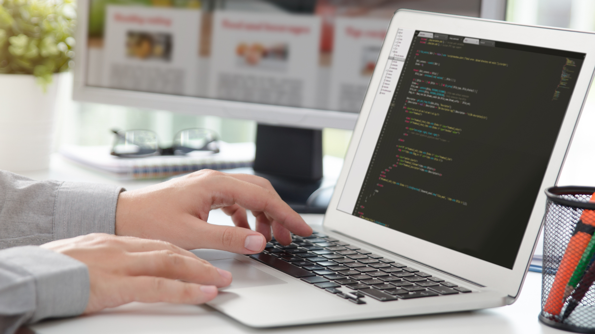 Web development workspace with screens showing code, and site layouts,