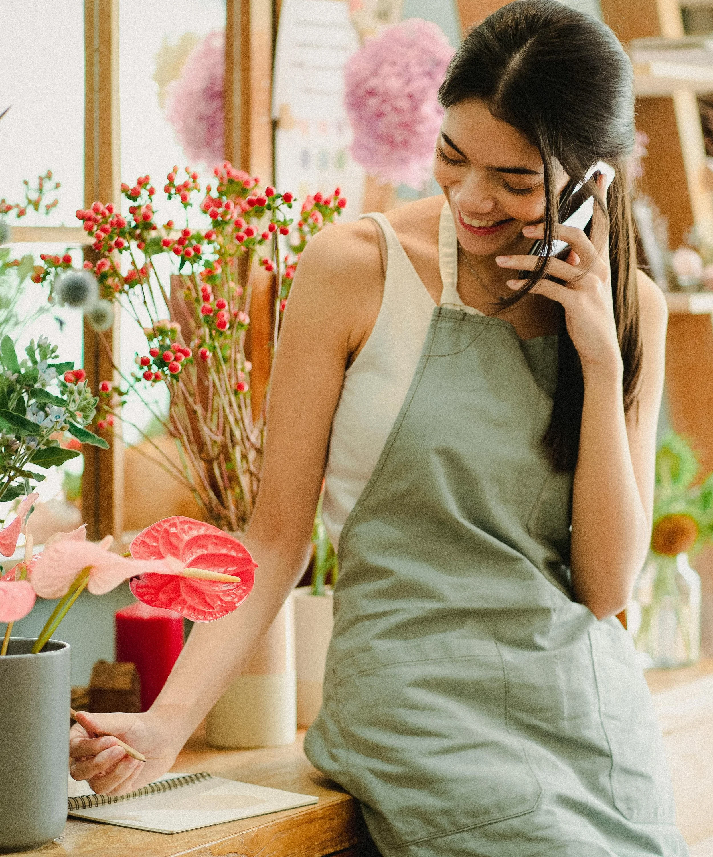 Smiling florist talking on the phone, representing friendly customer service and human connection in small business branding.