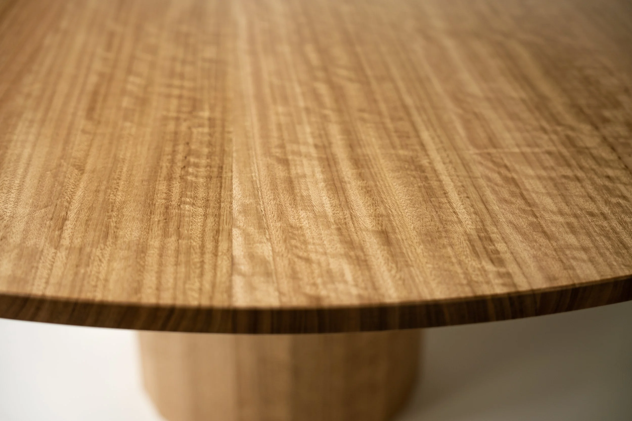 Close-up of a round wooden table with a smooth, polished surface and visible wood grain.